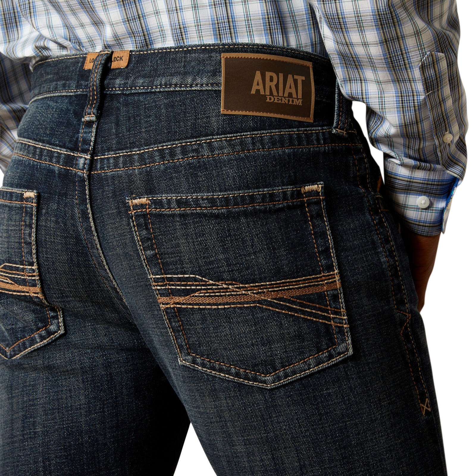 Ariat Men's M5 Keith Straight Leg Jean. Person wearing dark blue jeans and a plaid shirt on a white background