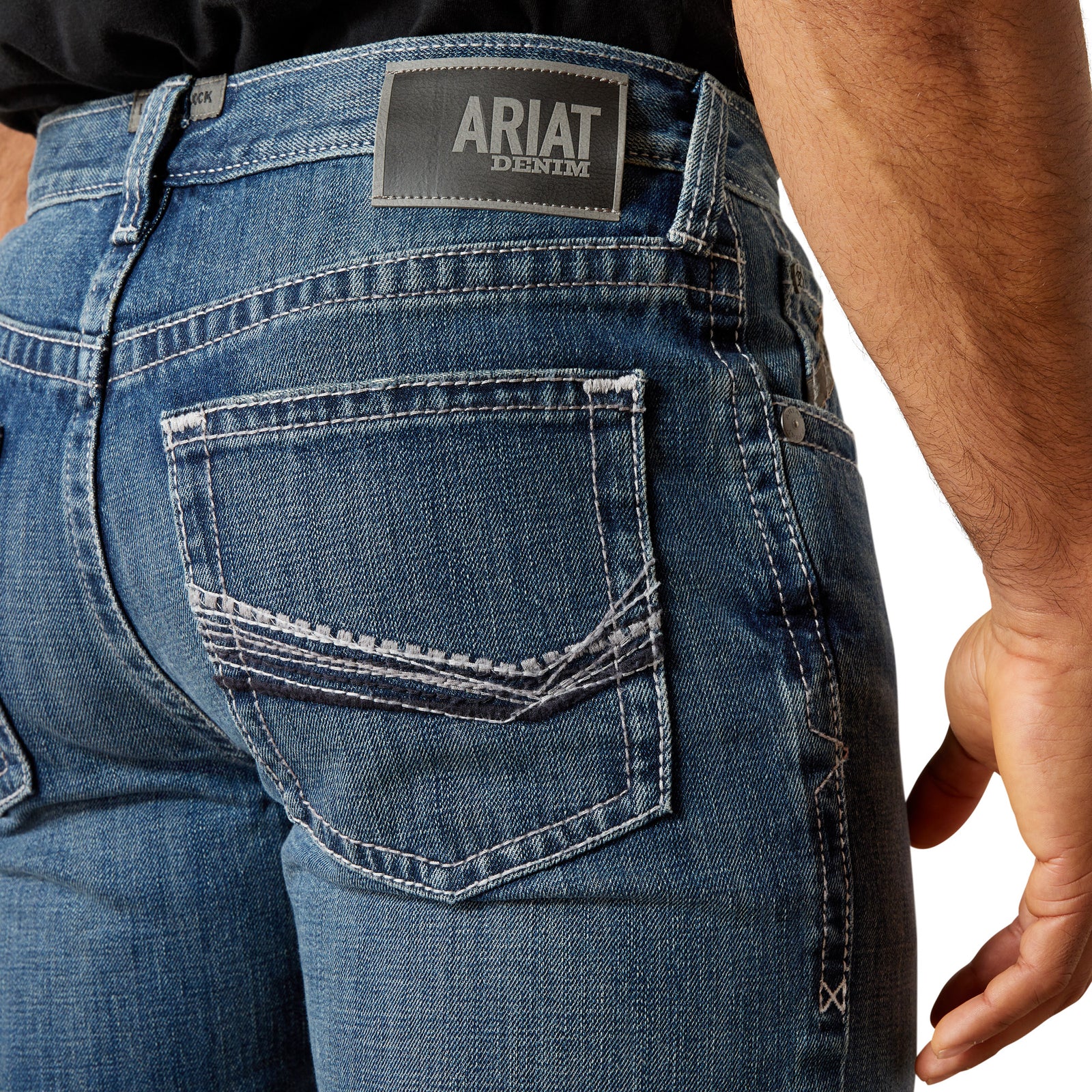Ariat Men's M4 August Relaxed Straight Leg Jean. Close-up of blue jeans with Ariat denim label on a white background