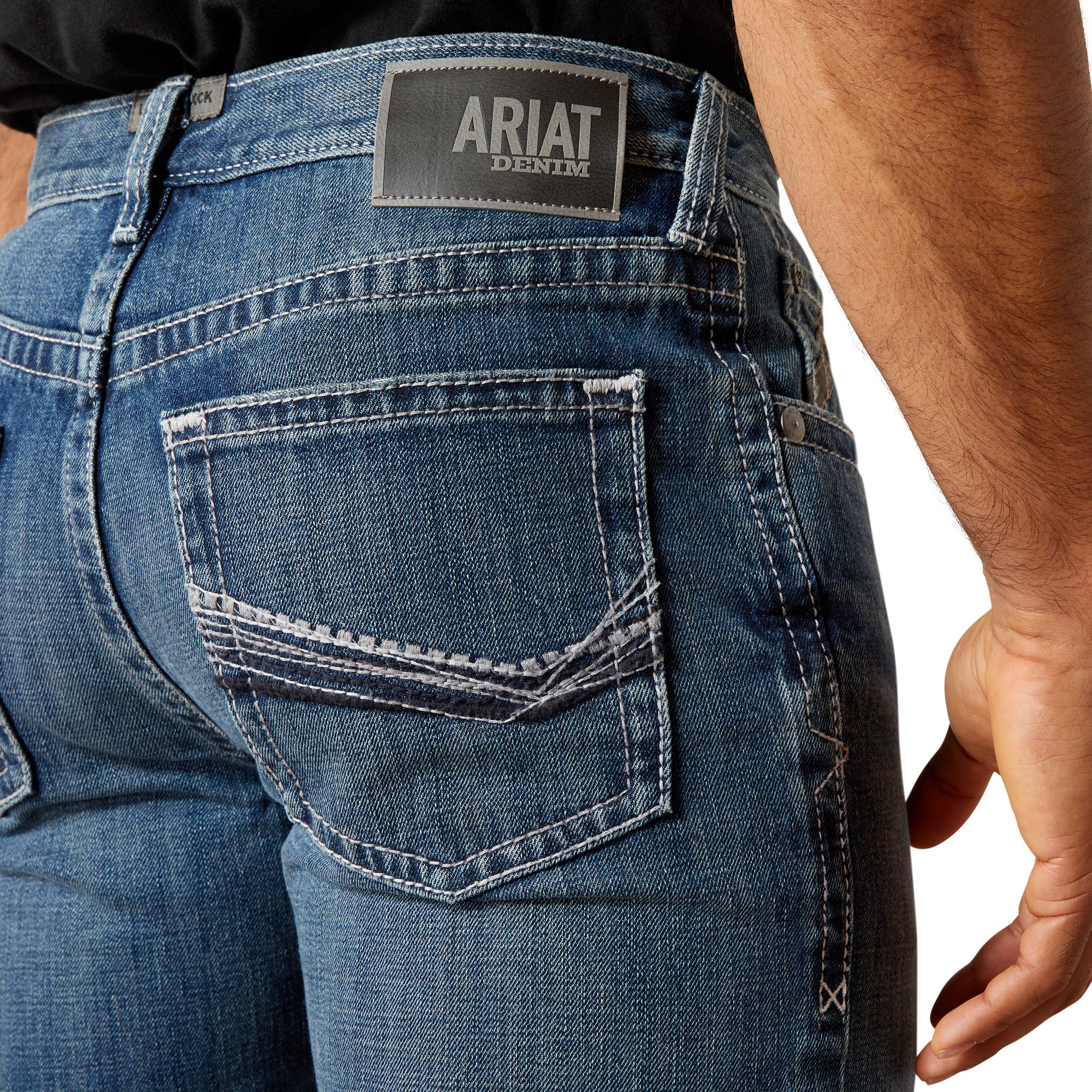 Ariat Men's M4 August Relaxed Straight Leg Jean. Close-up of blue jeans with Ariat denim label on a white background