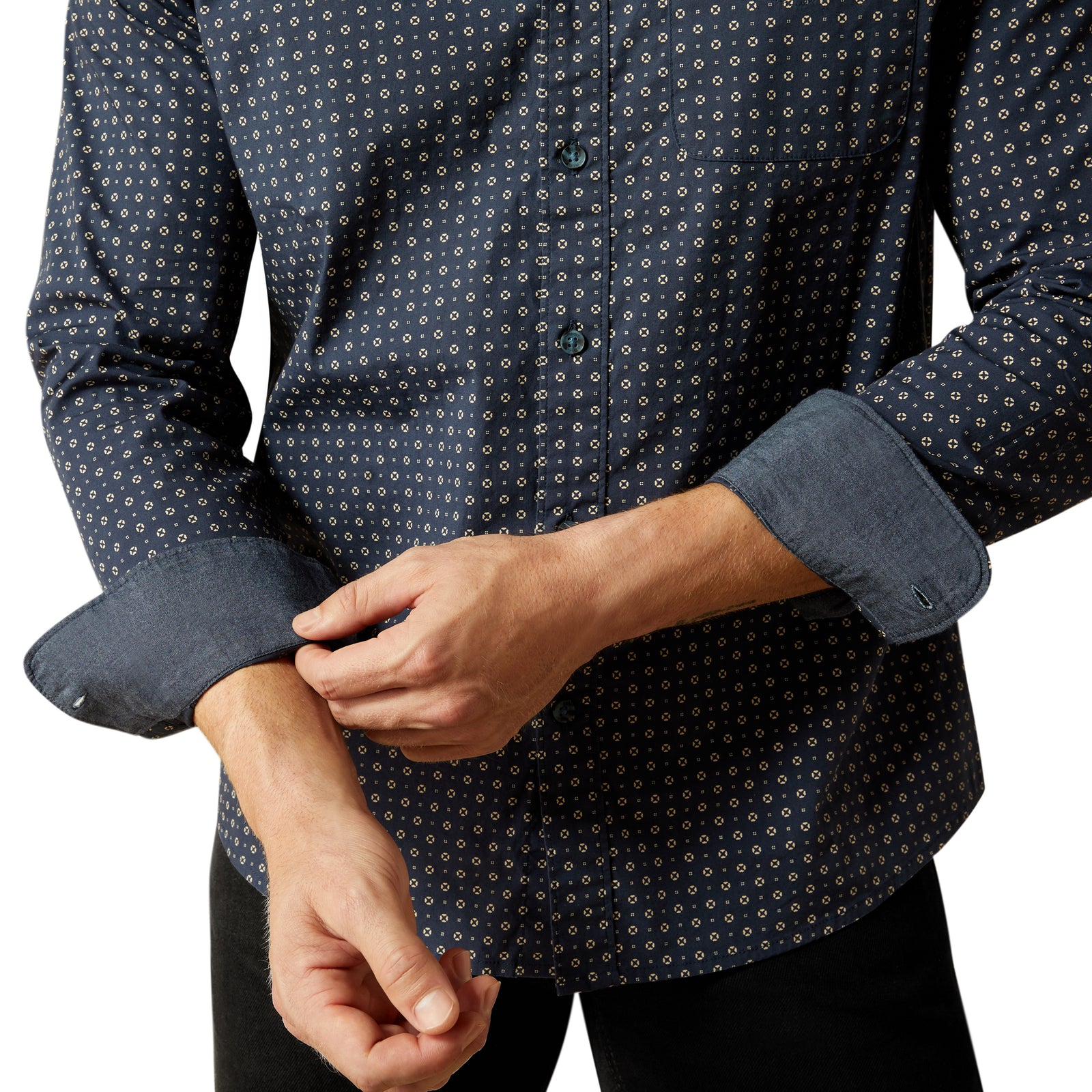 Close-up of a person wearing a dark blue patterned shirt with rolled-up sleeves.