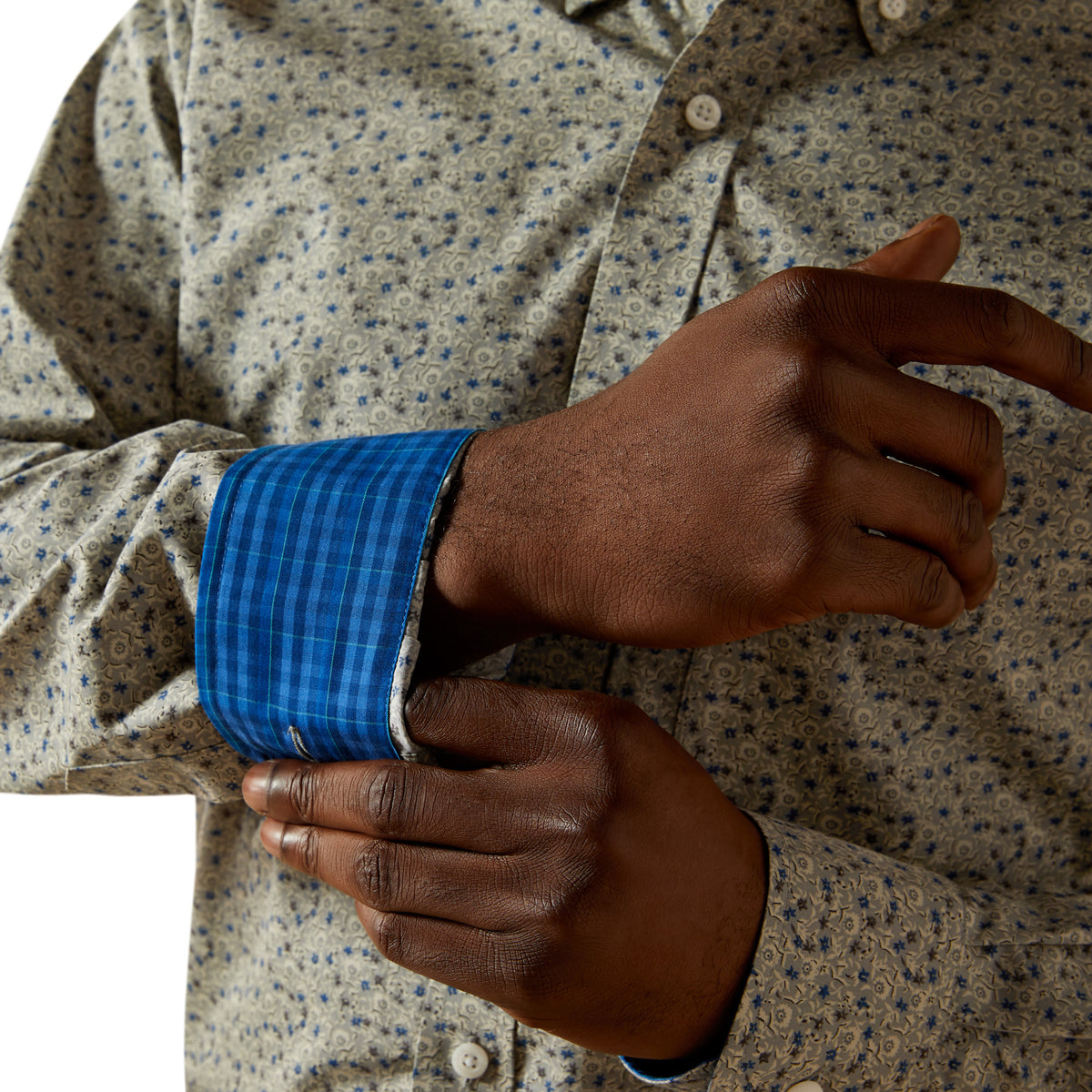 Close-up of a person wearing a patterned shirt with a blue cuff, focusing on the hands.