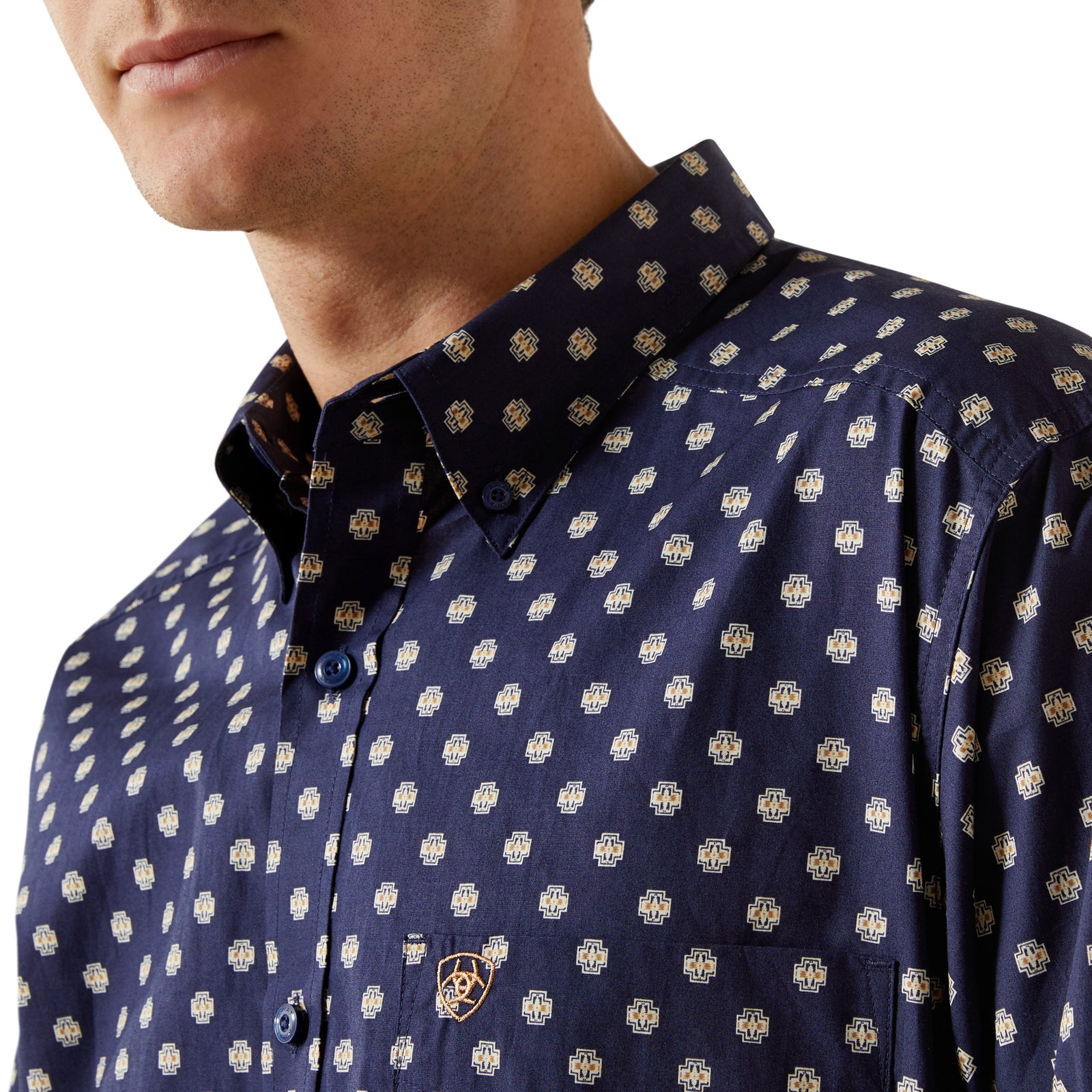 Man wearing a navy blue shirt with white polka dots and jeans on a white background