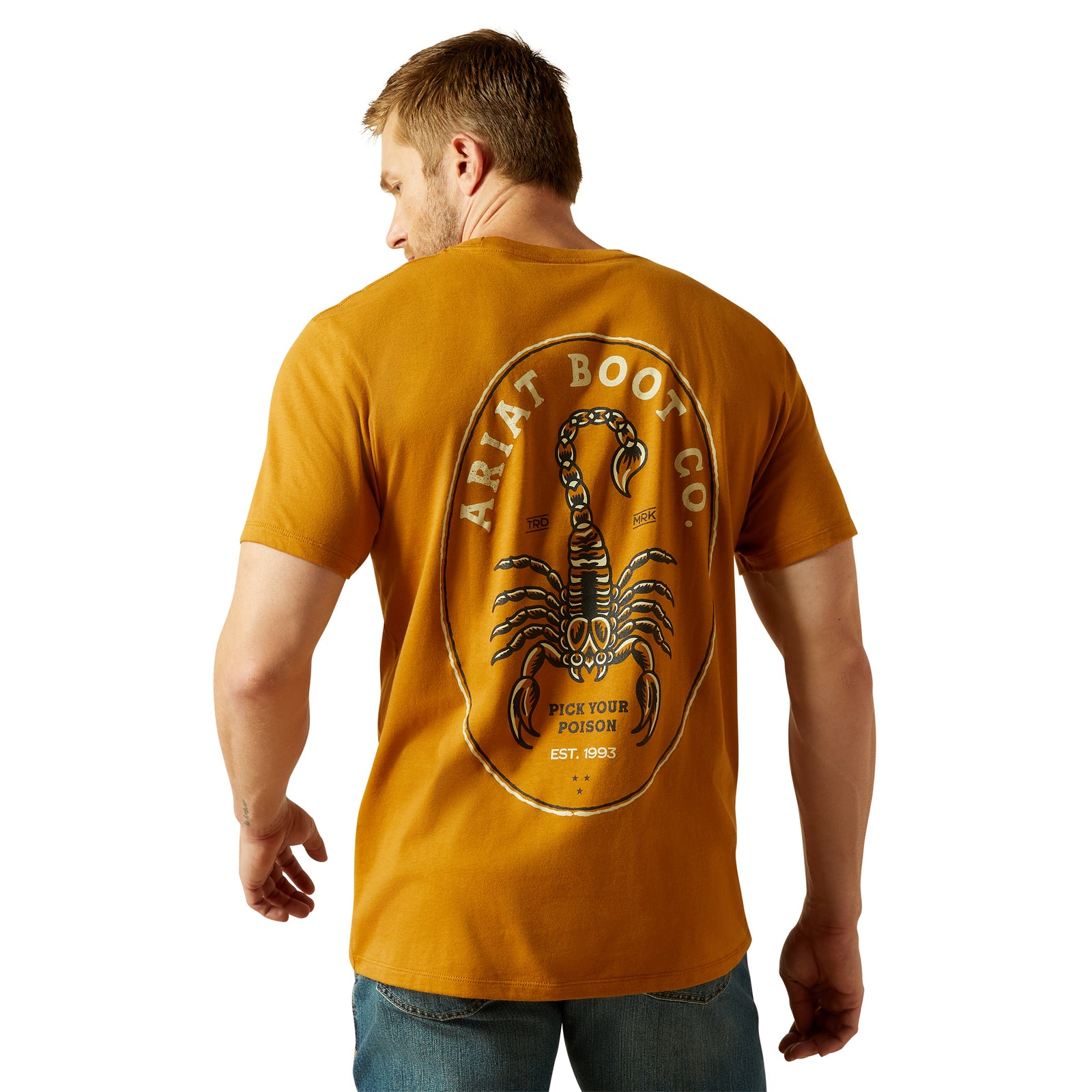 Ariat Men's Scorpion Seal T-Shirt. Man wearing a mustard yellow t-shirt with a scorpion logo on the back, on a white background