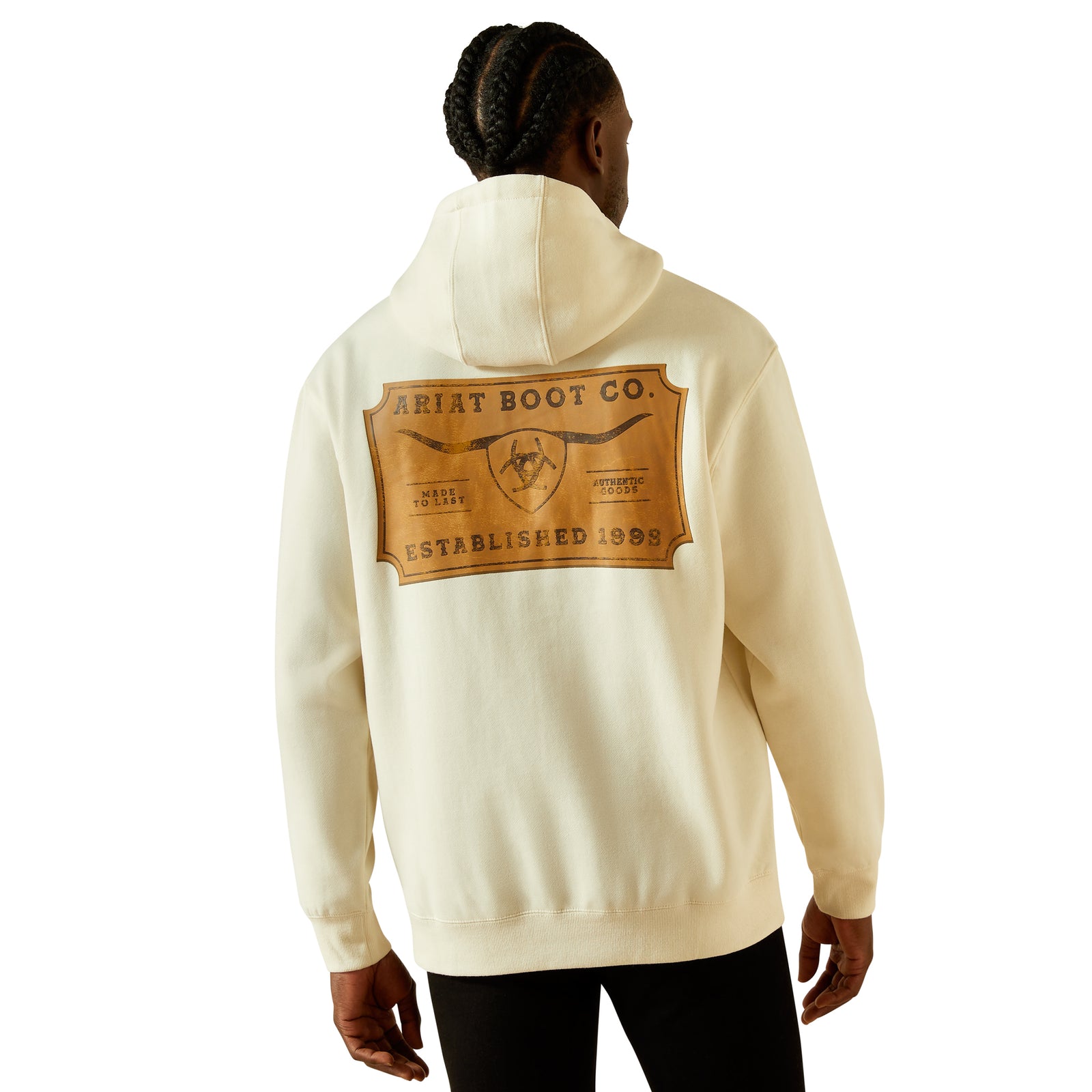 Person wearing a cream hoodie with Ariat Boot Co logo on the back against a white background