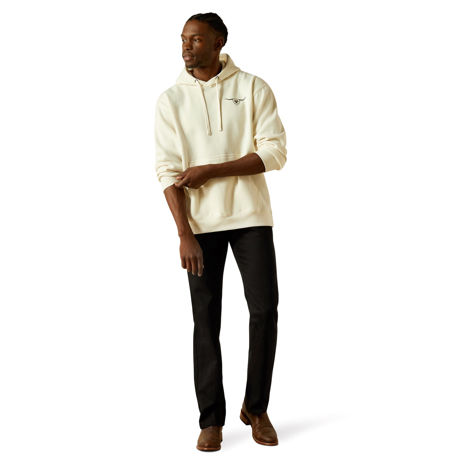 Man wearing a cream hoodie and black pants on a white background