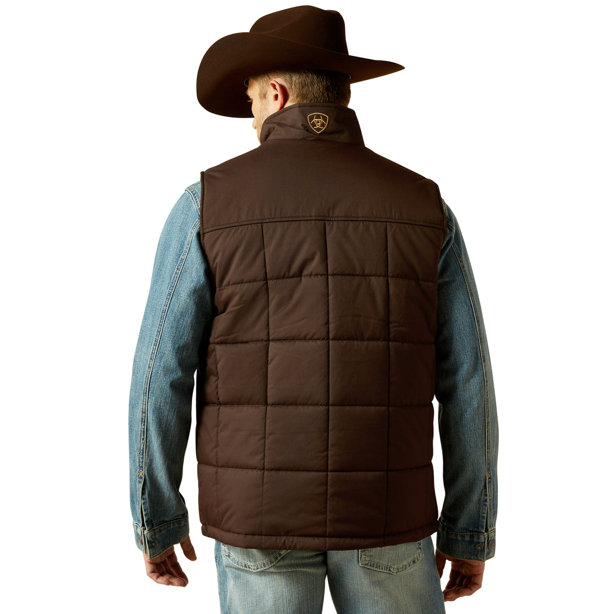 Man wearing a brown quilted vest over a denim shirt on a white background