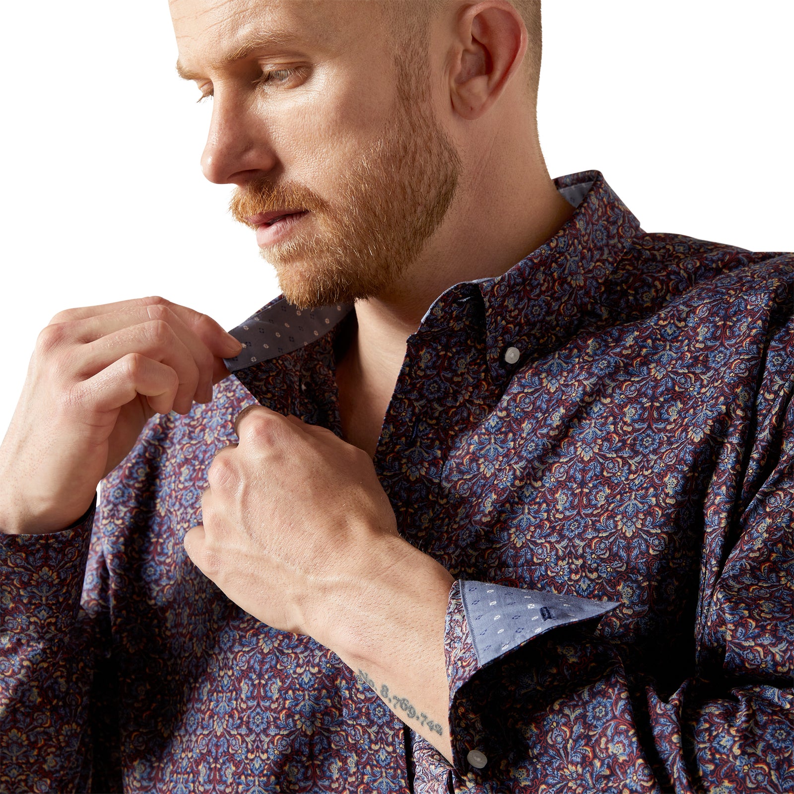 Man wearing a patterned shirt and jeans on a white background