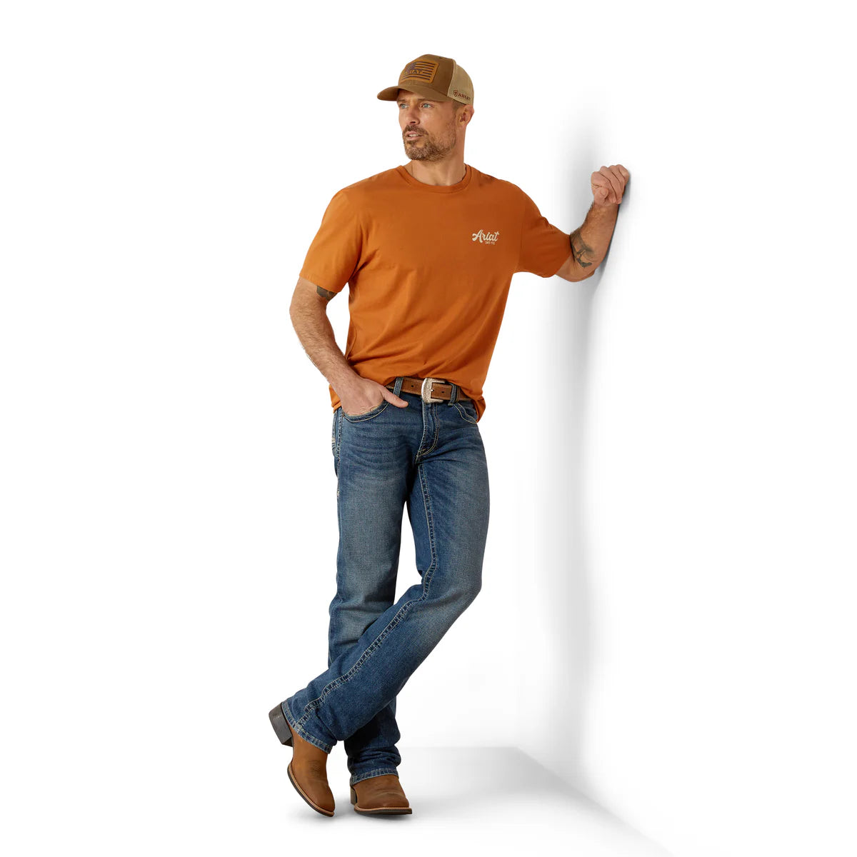 Man wearing an orange t-shirt and blue jeans standing against a white background