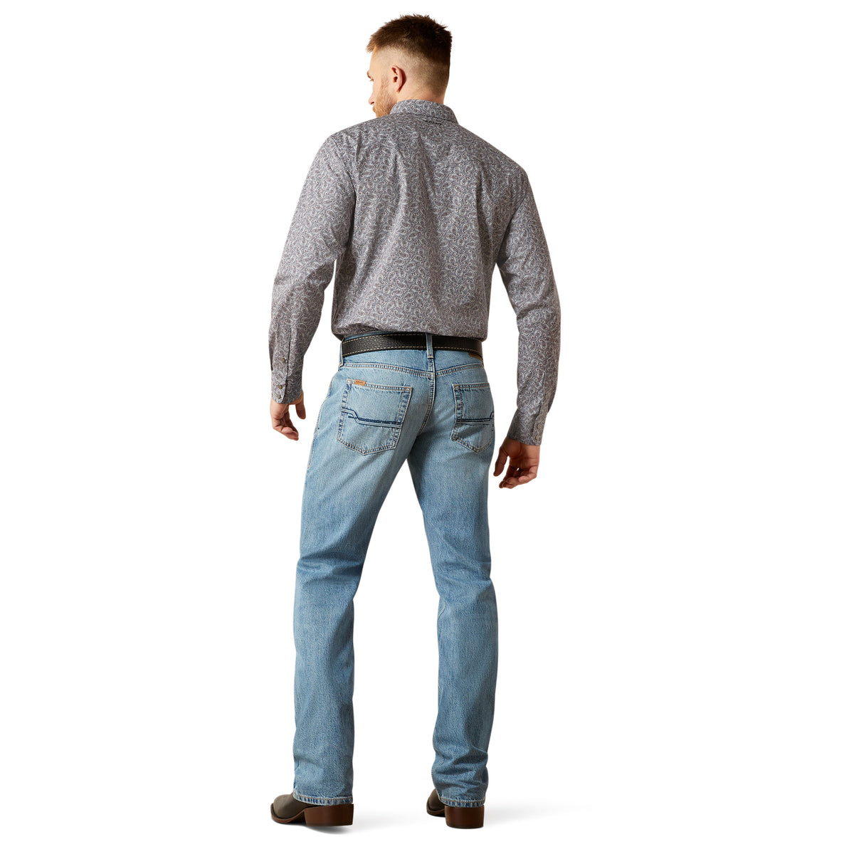 Man wearing a patterned shirt and light blue jeans on a white background