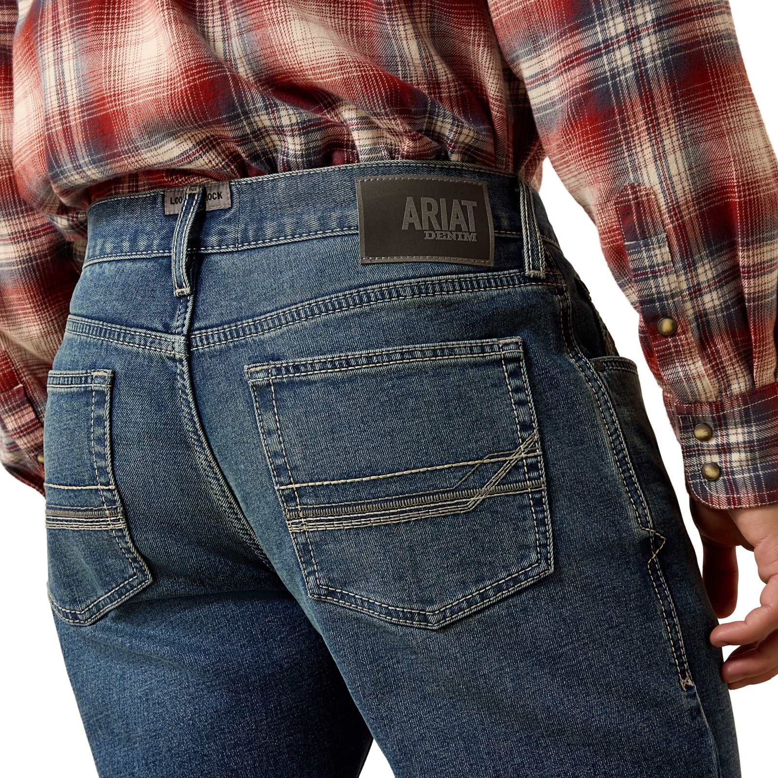 Person wearing blue jeans with Ariat branding on a white background