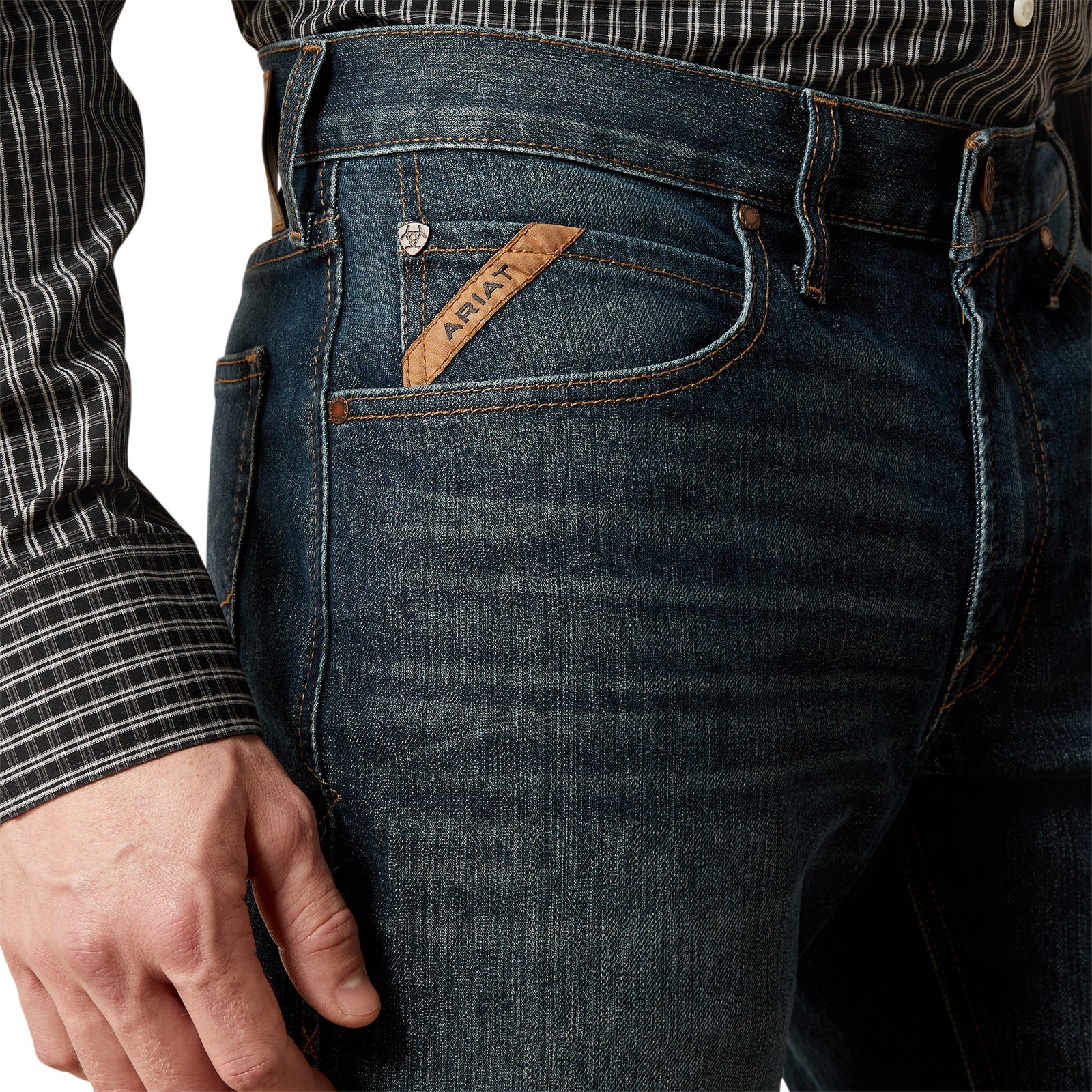 Close-up of a person wearing blue jeans with a brand label, on a white background.