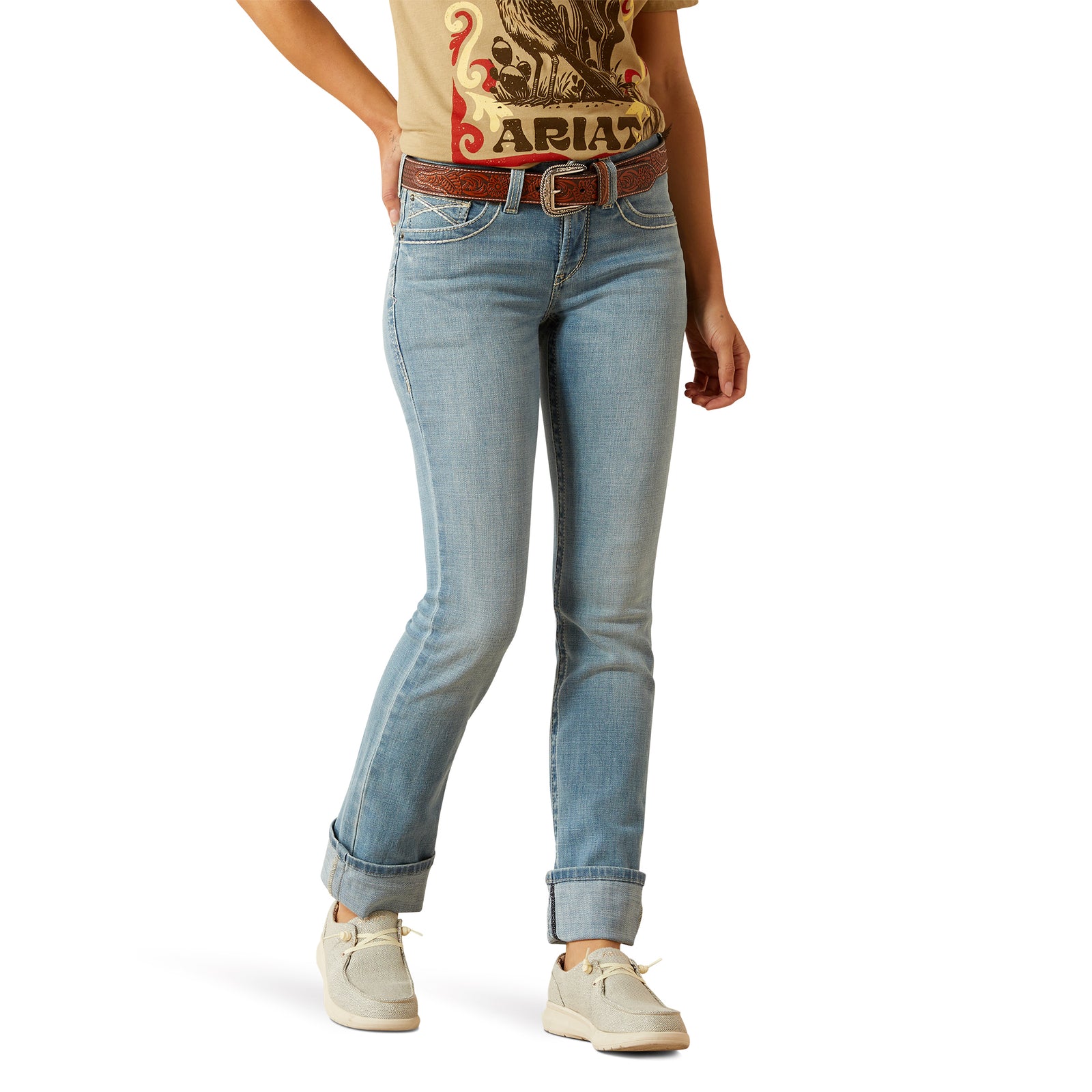 Ariat Women's Alina Perfect Rise Straight Leg Jean. Person wearing light blue jeans and a graphic t-shirt on a white background