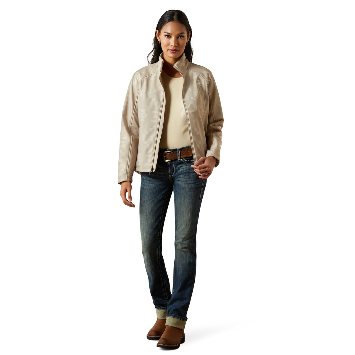 Woman wearing a beige jacket, white shirt, blue jeans, and brown boots on a white background