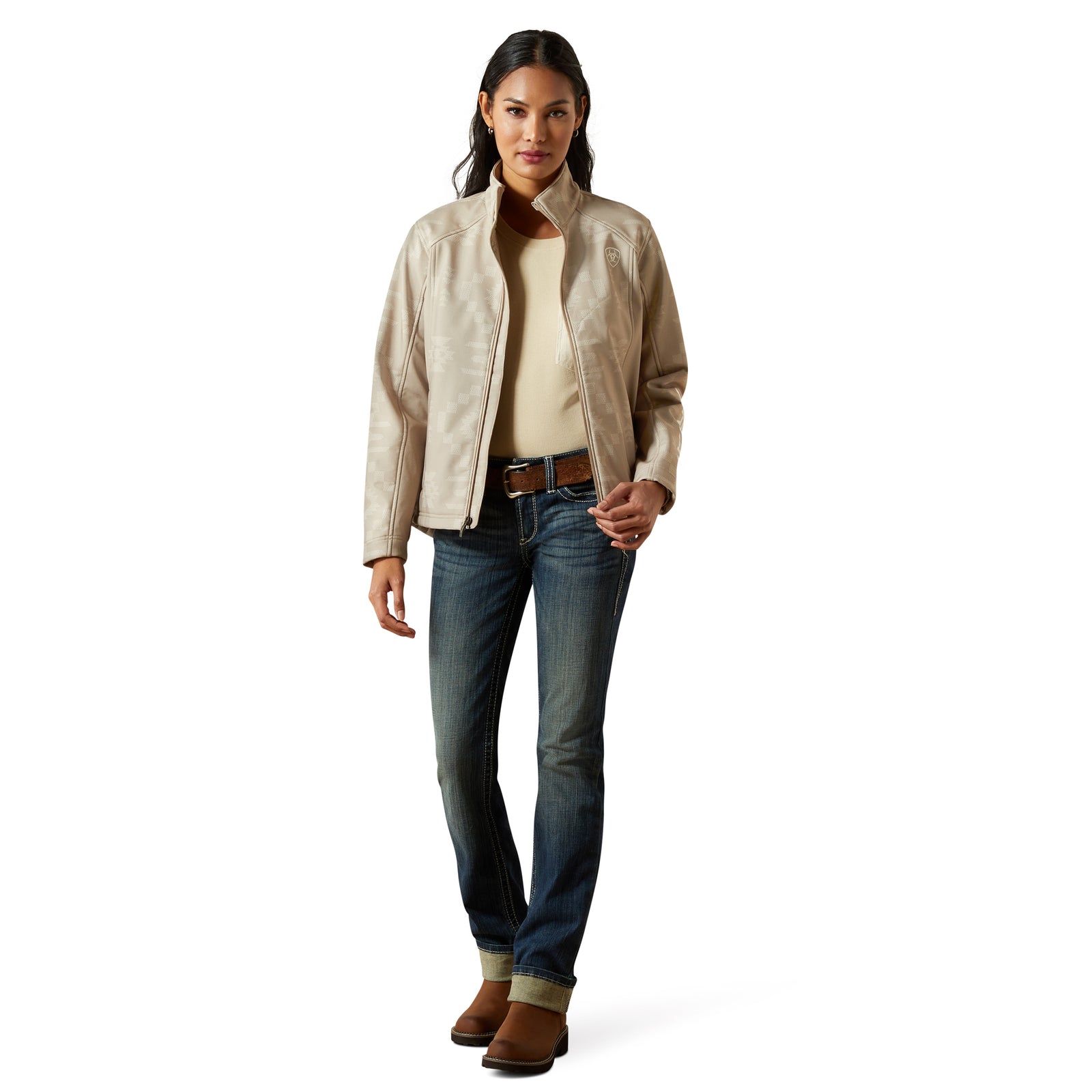 Woman wearing a beige jacket, white shirt, blue jeans, and brown boots on a white background