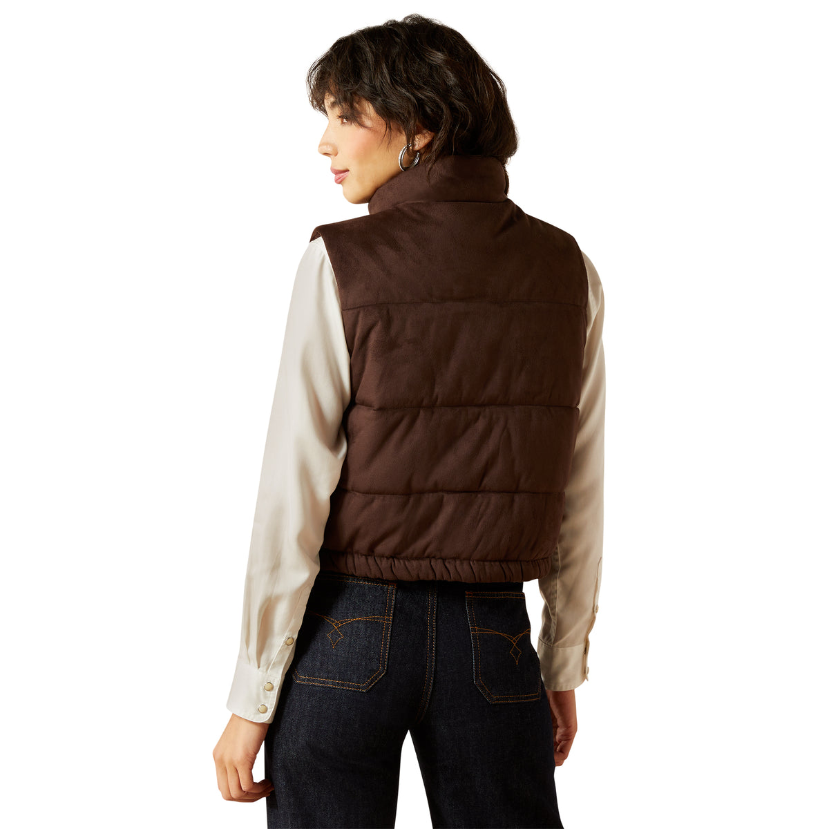 Person wearing a brown puffer vest over a cream shirt with a white background
