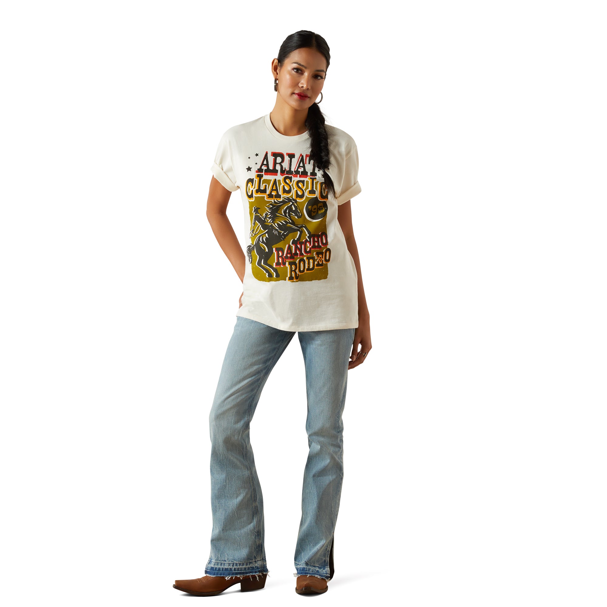 Ariat Women's Classic Rodeo T-Shirt. Woman wearing a white t-shirt with a graphic design and blue jeans on a white background