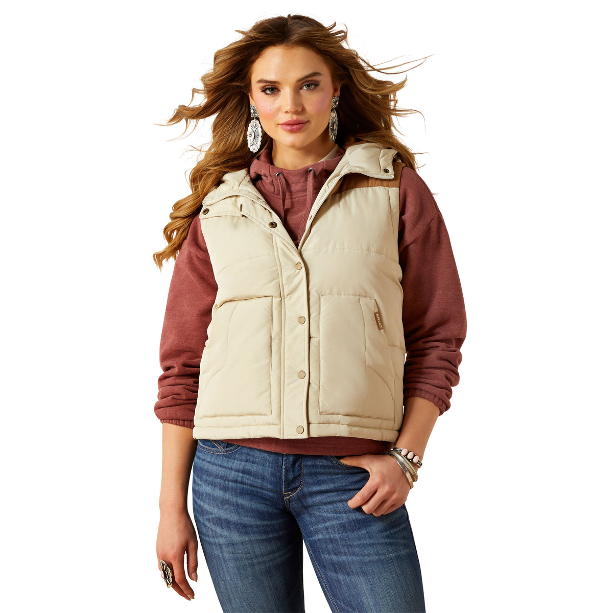 Woman wearing a beige puffer vest over a red shirt on a white background
