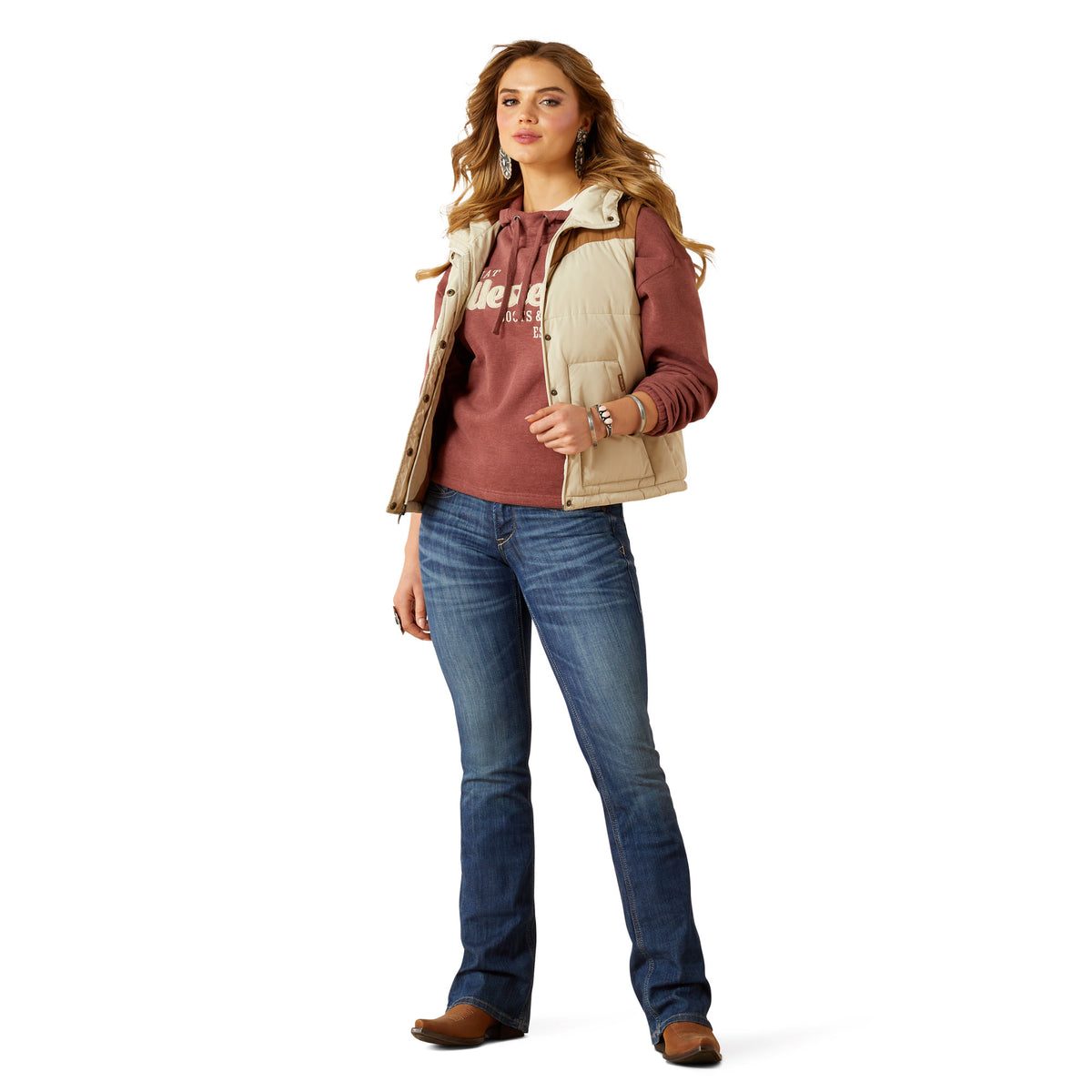 Woman wearing a red hoodie, beige vest, blue jeans, and brown shoes on a white background
