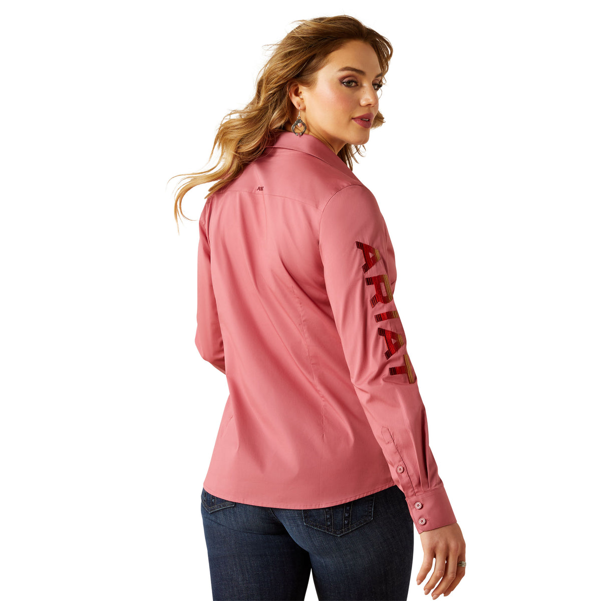 Woman wearing a pink long-sleeve shirt with 'ARIAT' text on a white background