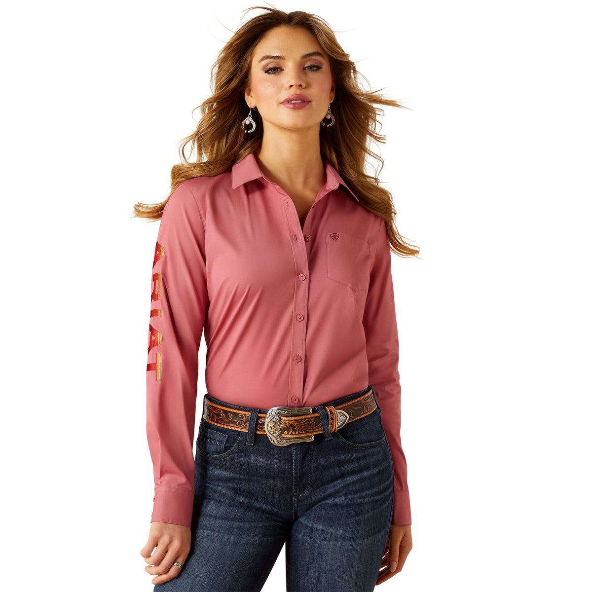Woman wearing a pink shirt with a logo on the sleeve and blue jeans against a white background