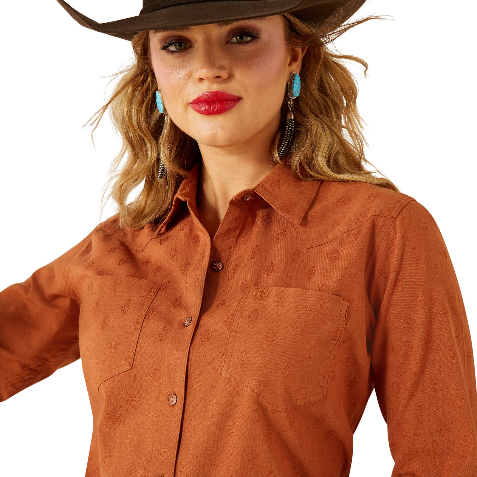 Woman wearing a brown cowboy hat and shirt with turquoise earrings on a white background