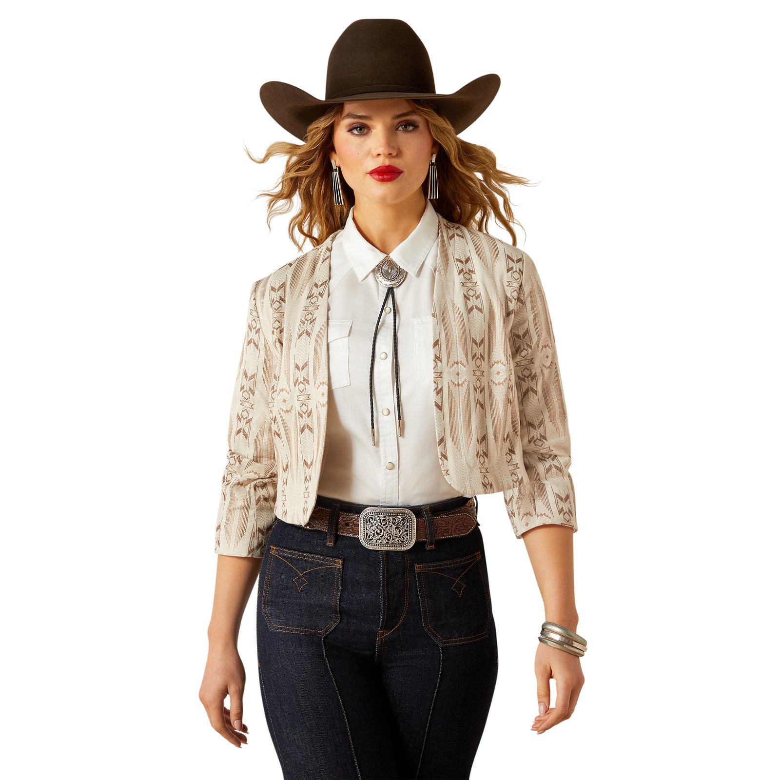 Woman wearing a cowboy hat, white blouse, patterned jacket, and dark jeans on a white background
