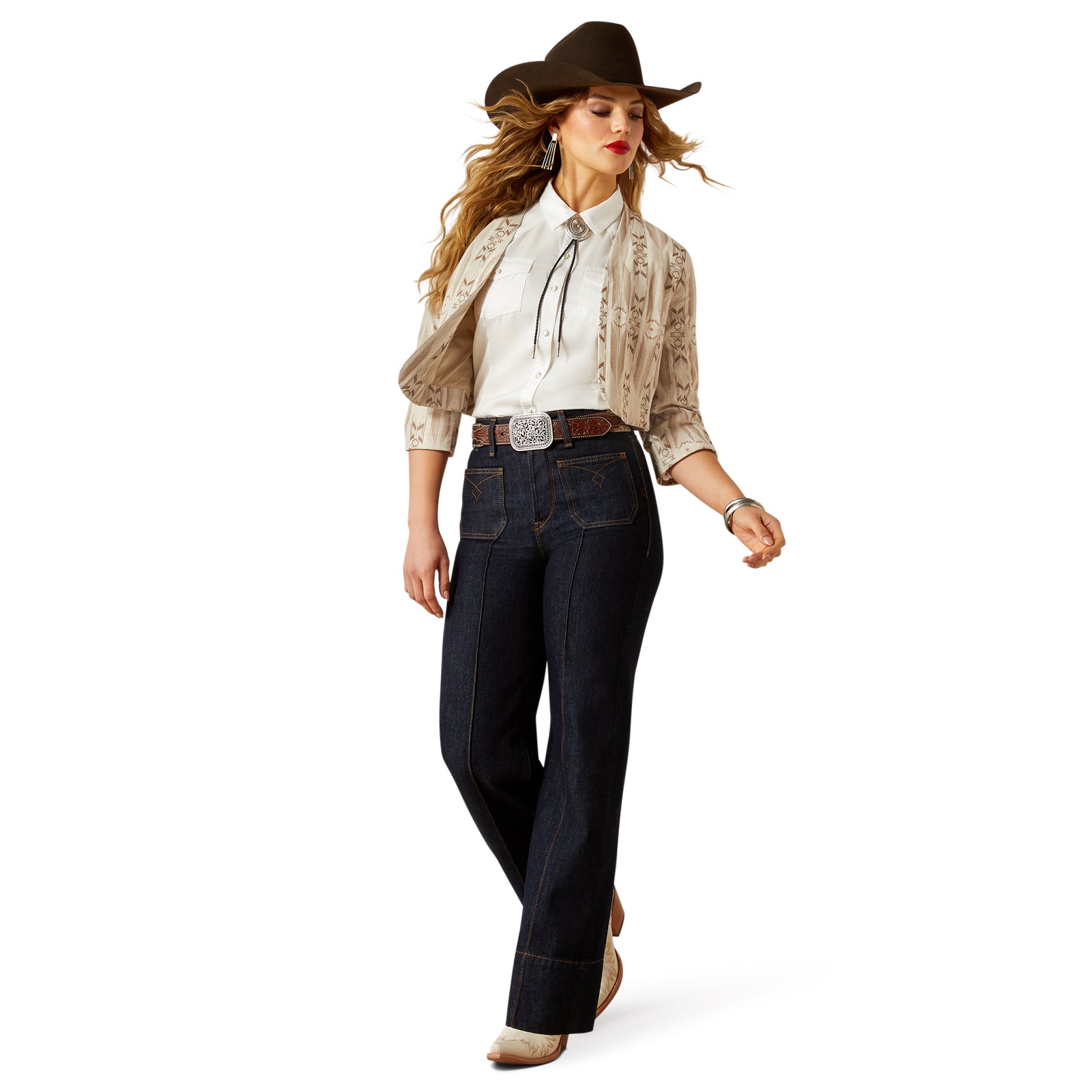 Woman wearing a cowboy hat, beige blouse, dark jeans, and brown boots on a white background