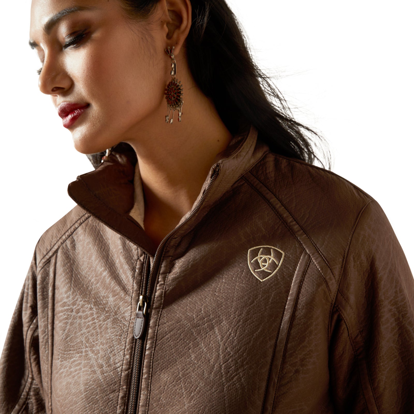 Close-up of a woman wearing a brown leather jacket with a brand logo on a white background