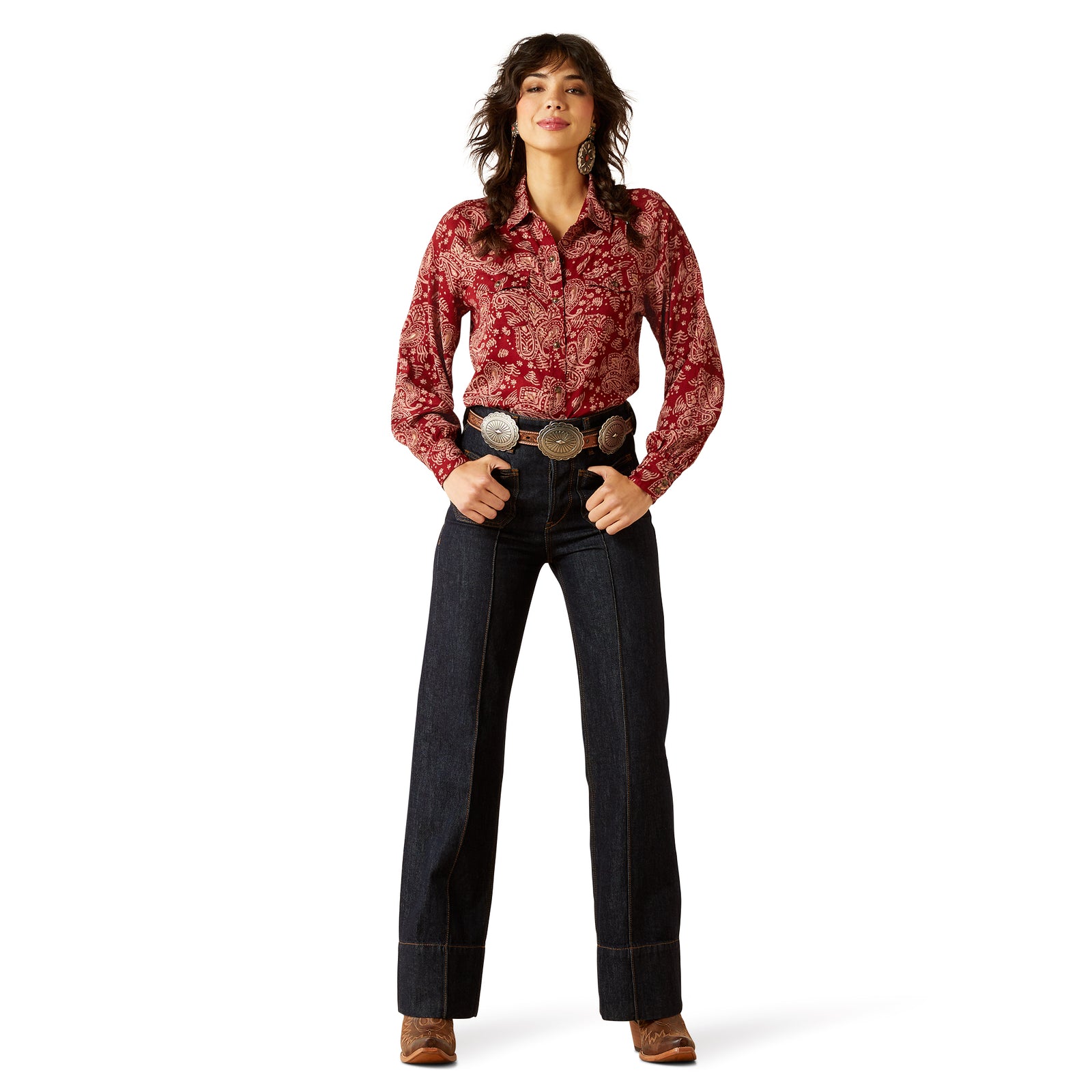 Woman wearing a red patterned shirt and dark jeans on a white background