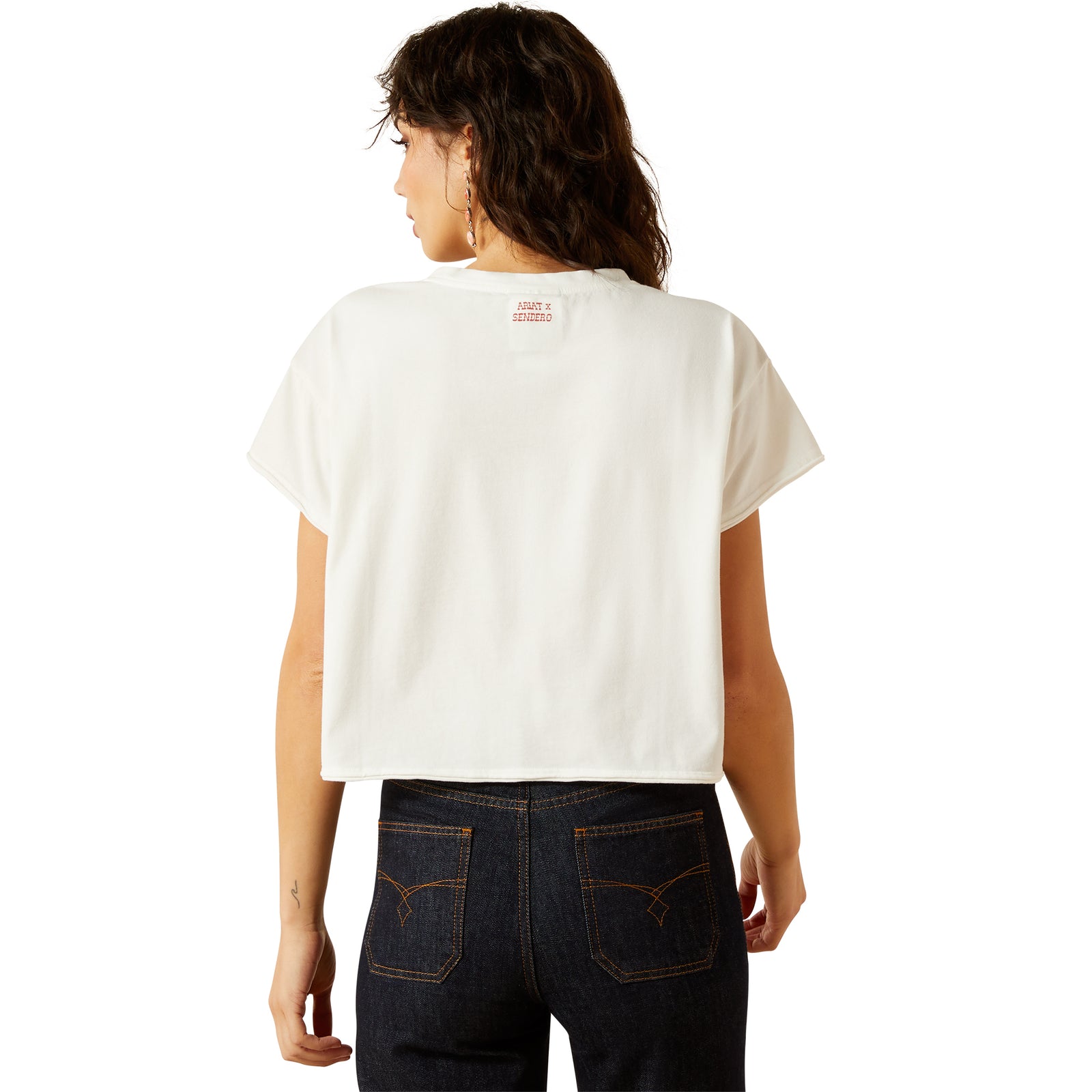 Ariat Women's Sendero Yeehaw S/S T-Shirt. Person wearing a white t-shirt with a logo on the back, standing against a white background