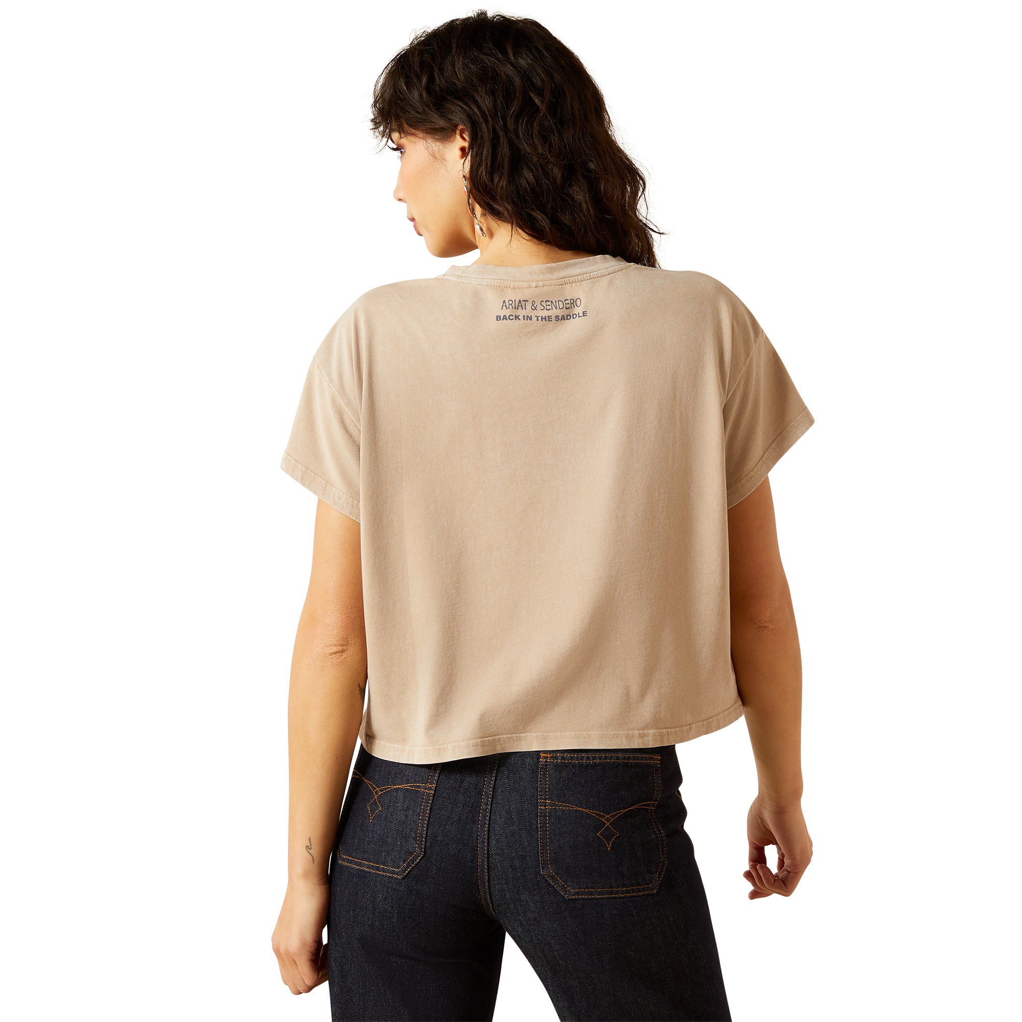 Ariat Women's Sendero x Wild West Country Fest S/S T-ShirtPerson wearing a beige t-shirt with text on the back, standing against a white background 