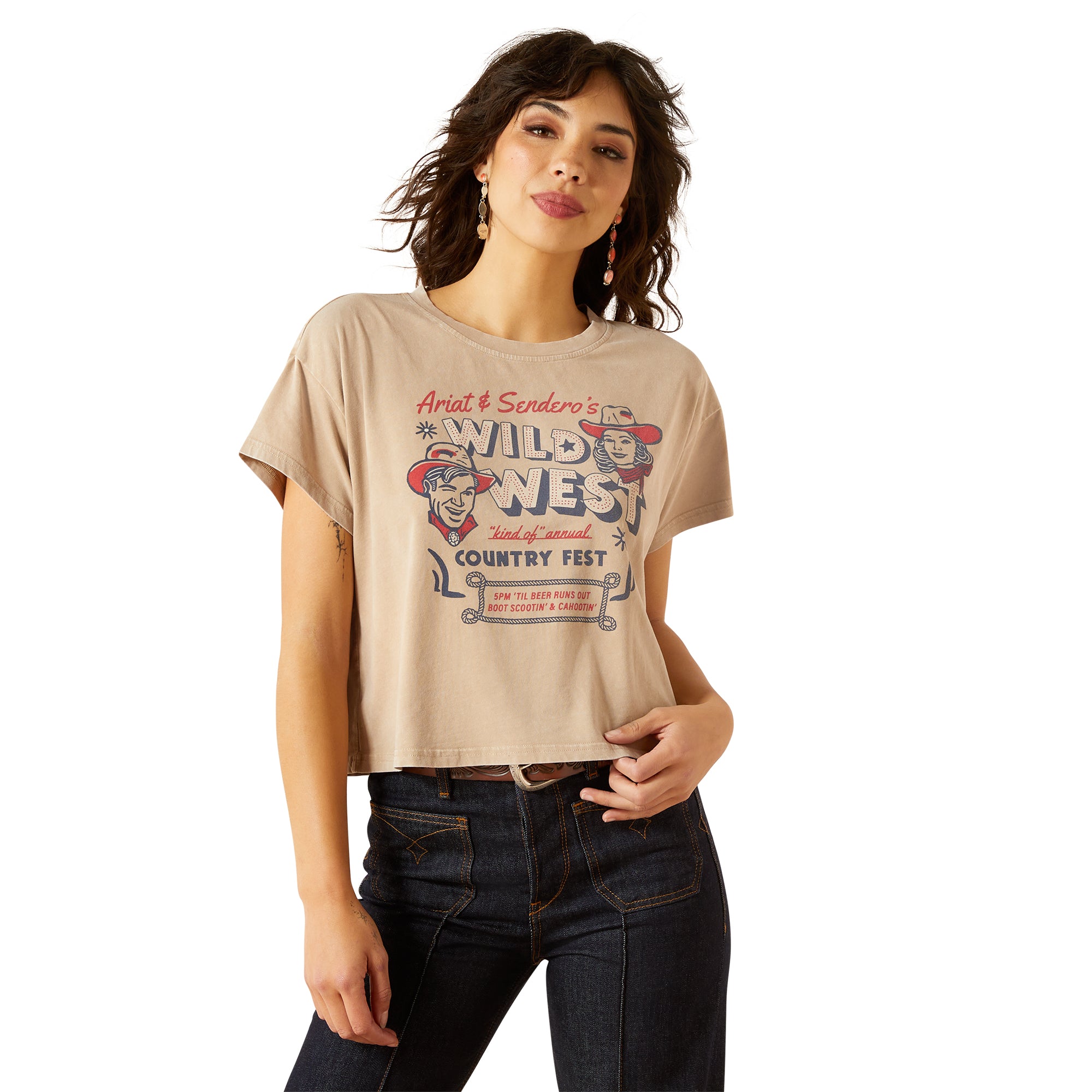 Ariat Women's Sendero x Wild West Country Fest S/S T-Shirt. Woman wearing a beige t-shirt with graphic design on a white background