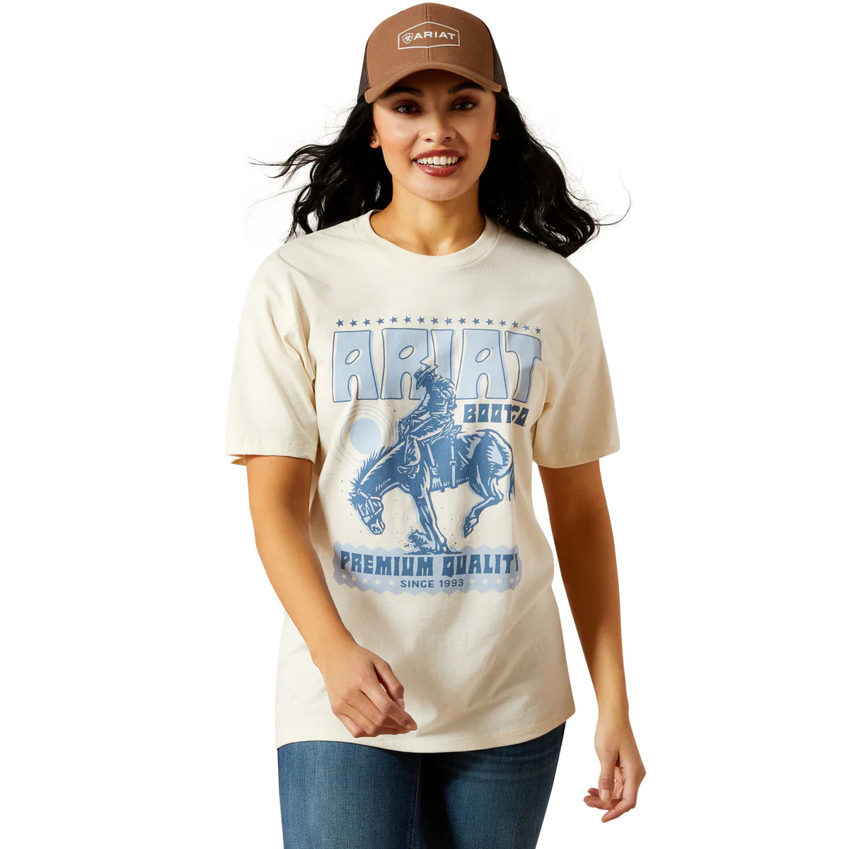 Woman wearing a cream t-shirt with a graphic design and a brown cap on a white background