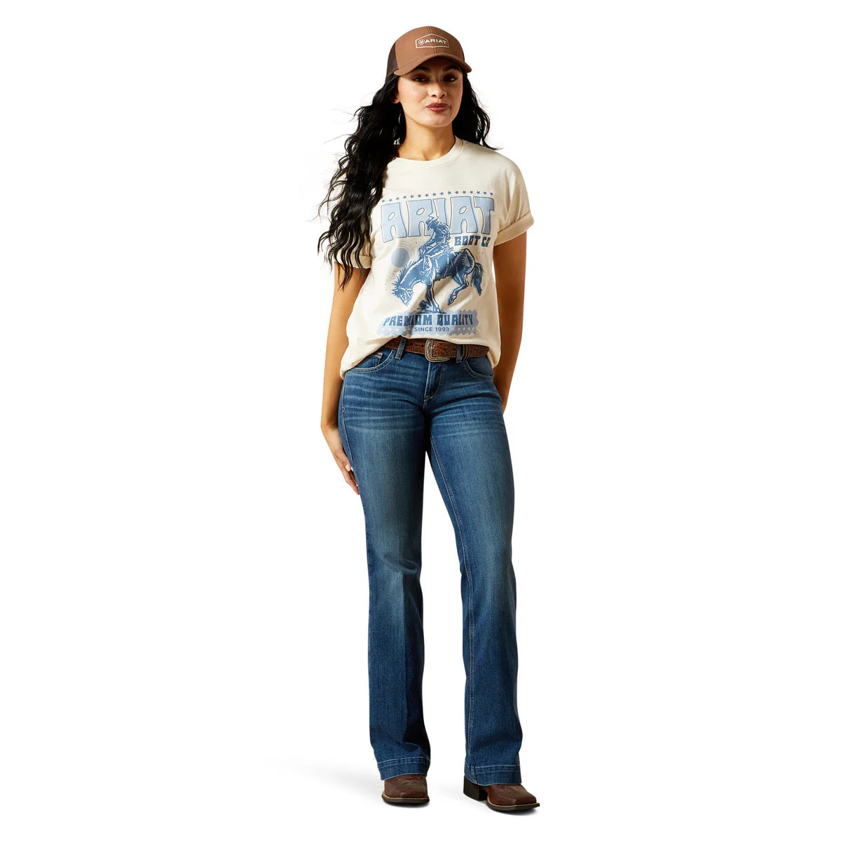 Woman wearing a graphic t-shirt, jeans, and cap on a white background