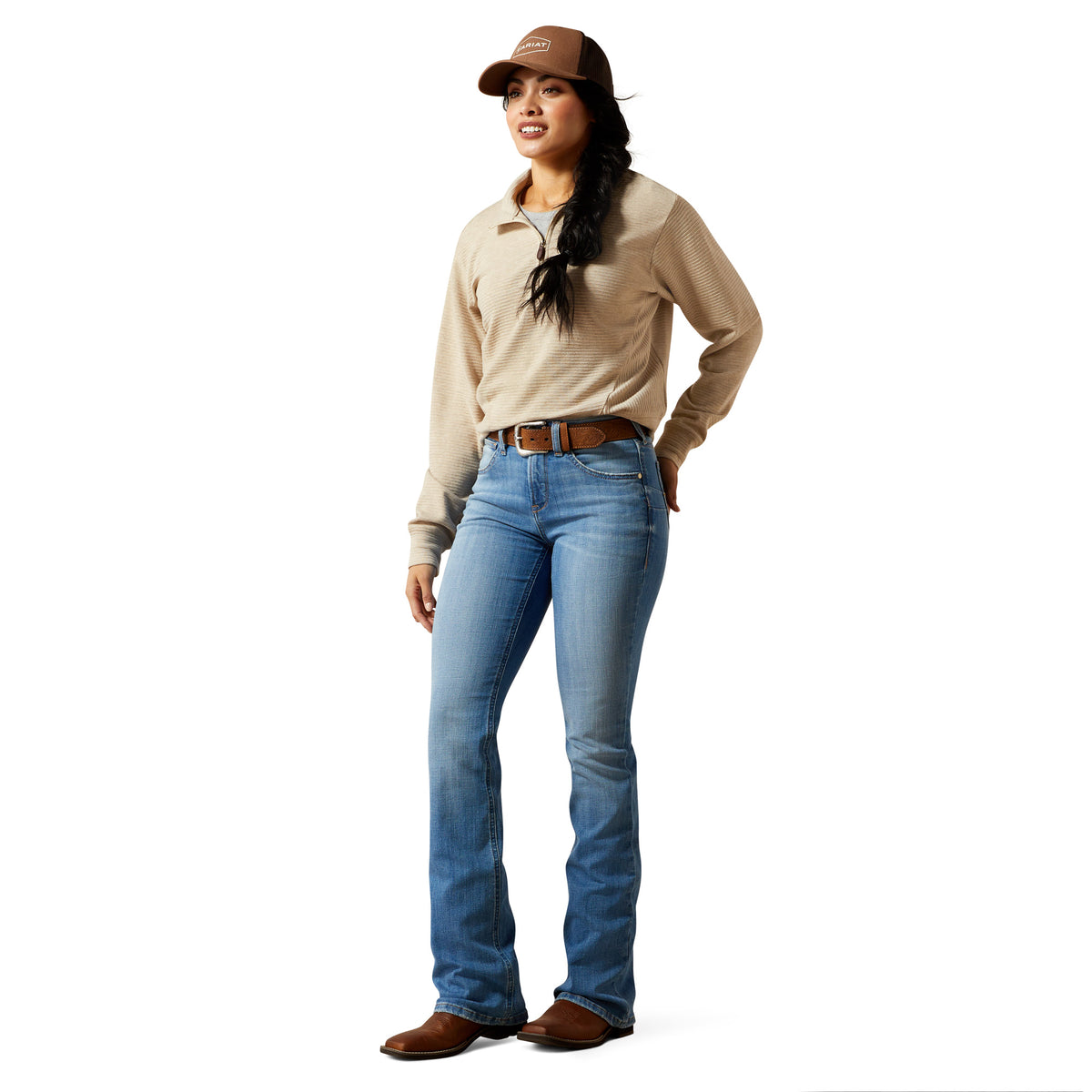 Woman wearing a beige shirt, blue jeans, and a brown cap on a white background