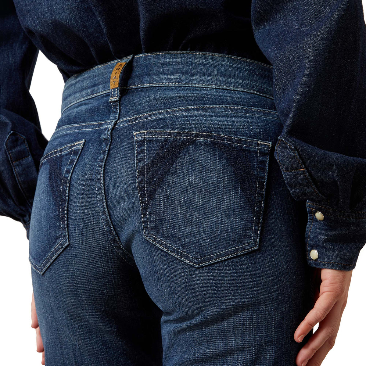 Person wearing blue jeans with a focus on the back pocket and waistband.