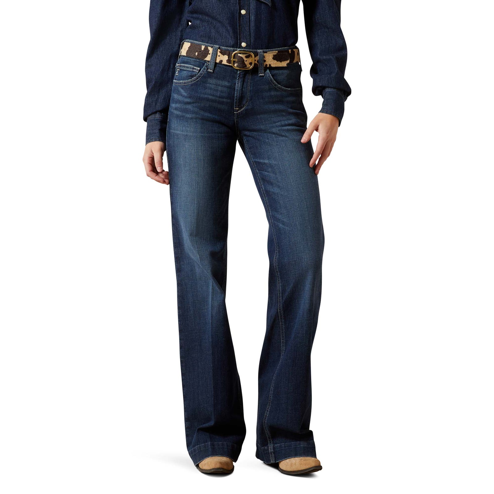 Person wearing blue jeans with a patterned belt on a white background