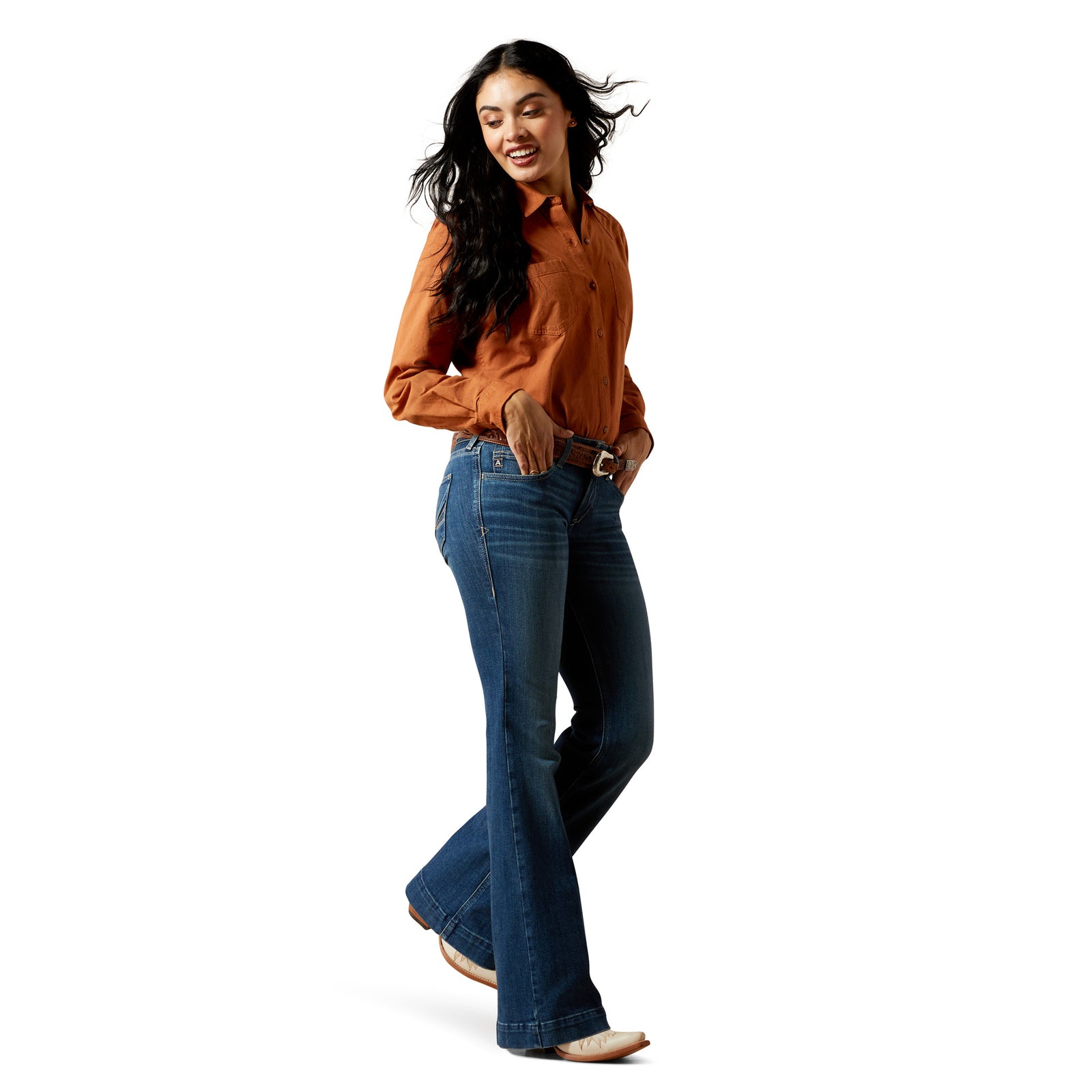 Woman wearing a rust-colored shirt and blue flared jeans on a white background