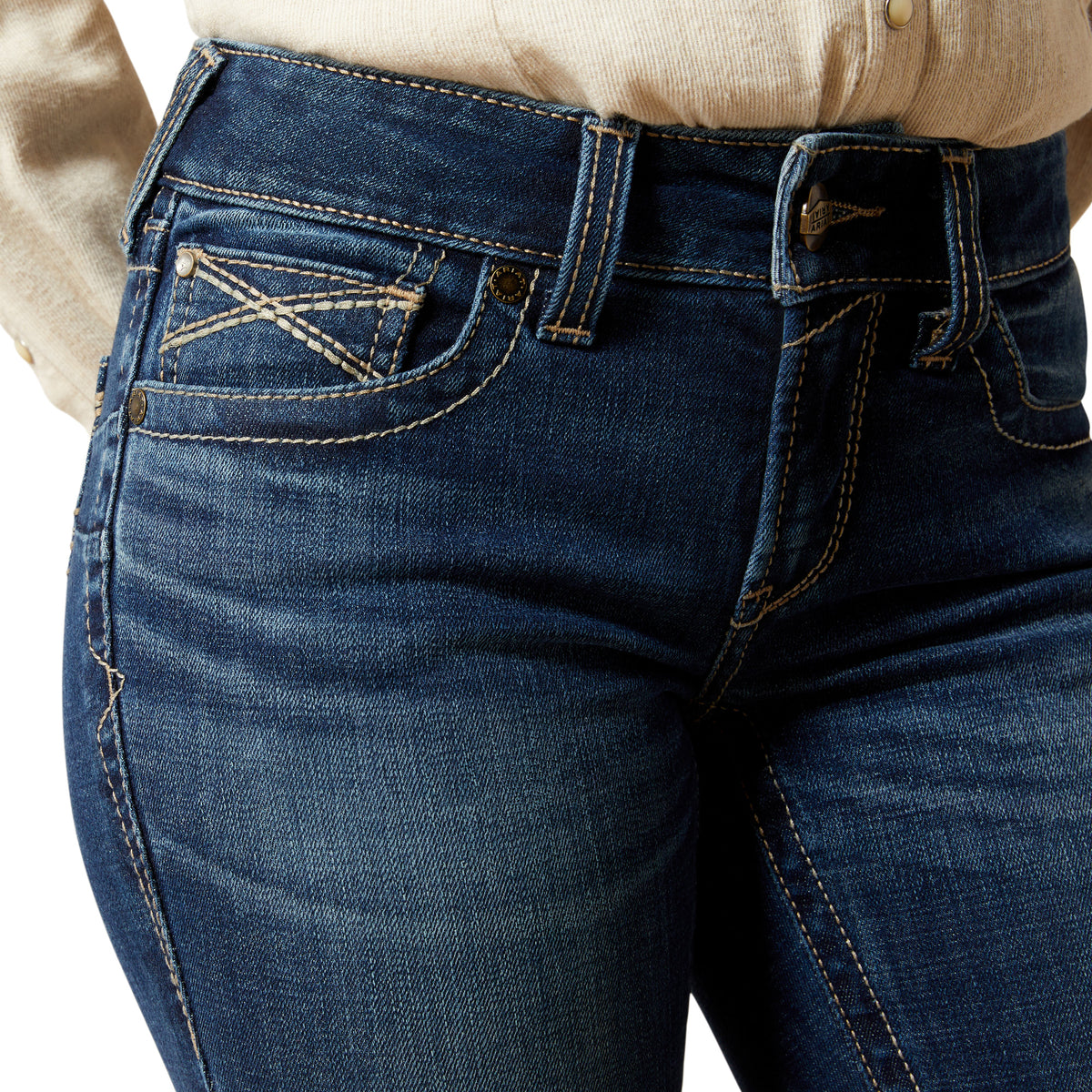 Close-up of blue jeans with a beige shirt underneath on a white background