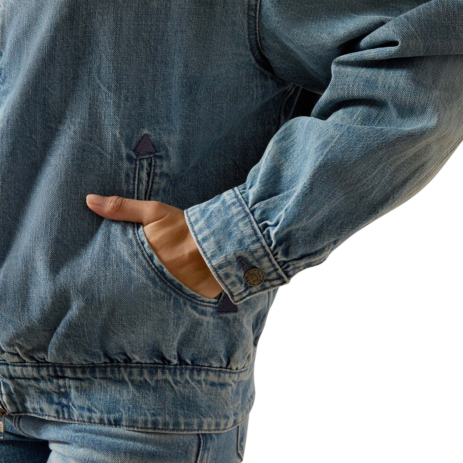 Close-up of a person wearing a blue denim jacket with a hand in the pocket on a white background