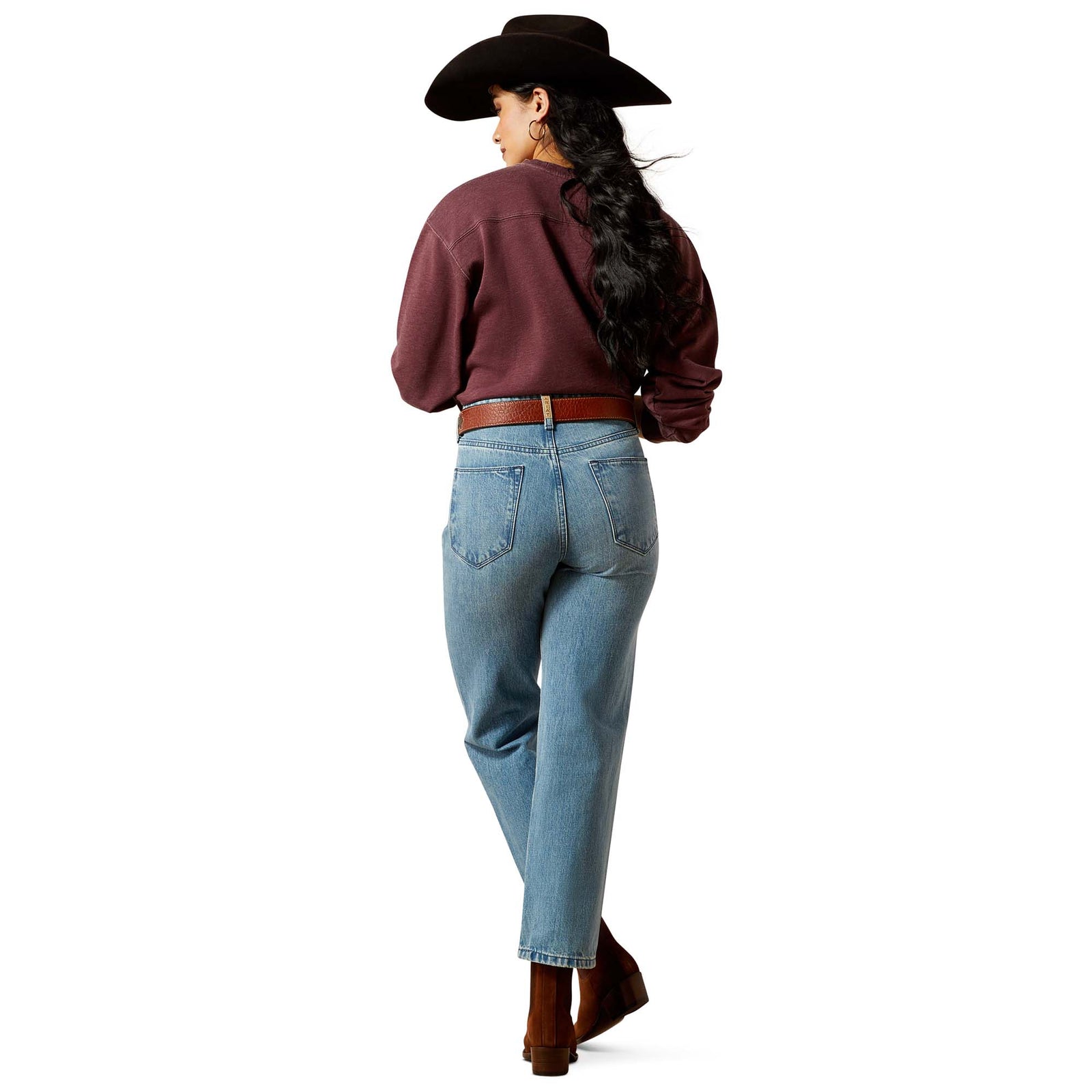 Person wearing light blue jeans and brown shoes on a white background