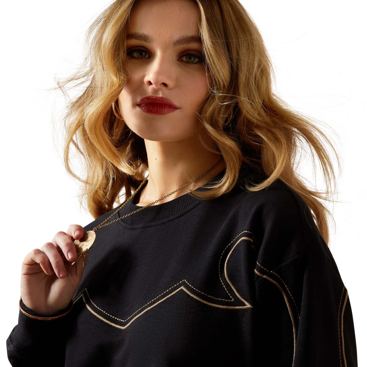 Woman wearing a black sweater with decorative stitching on a beige background