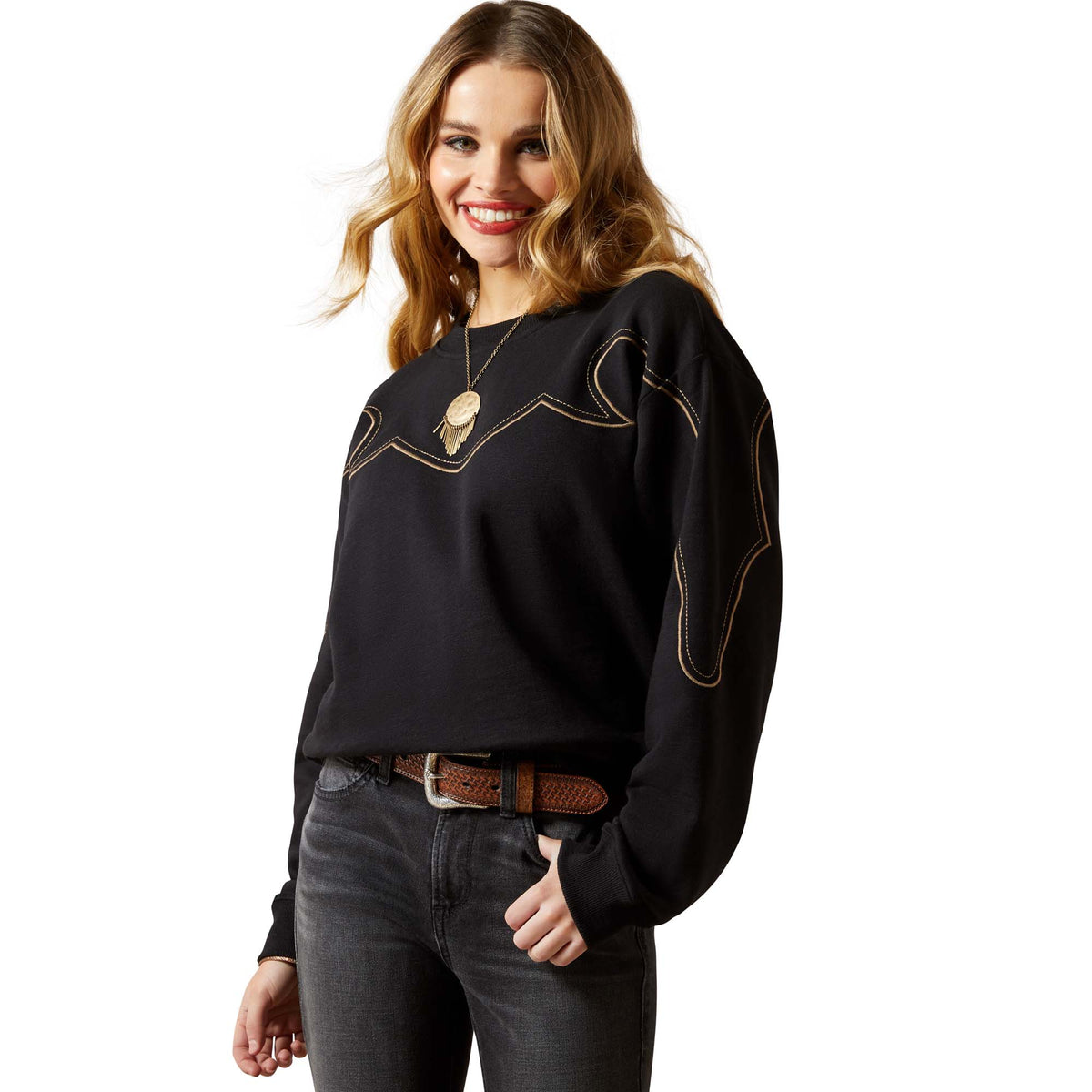 Woman wearing a black sweater with gold accents and gray jeans on a white background