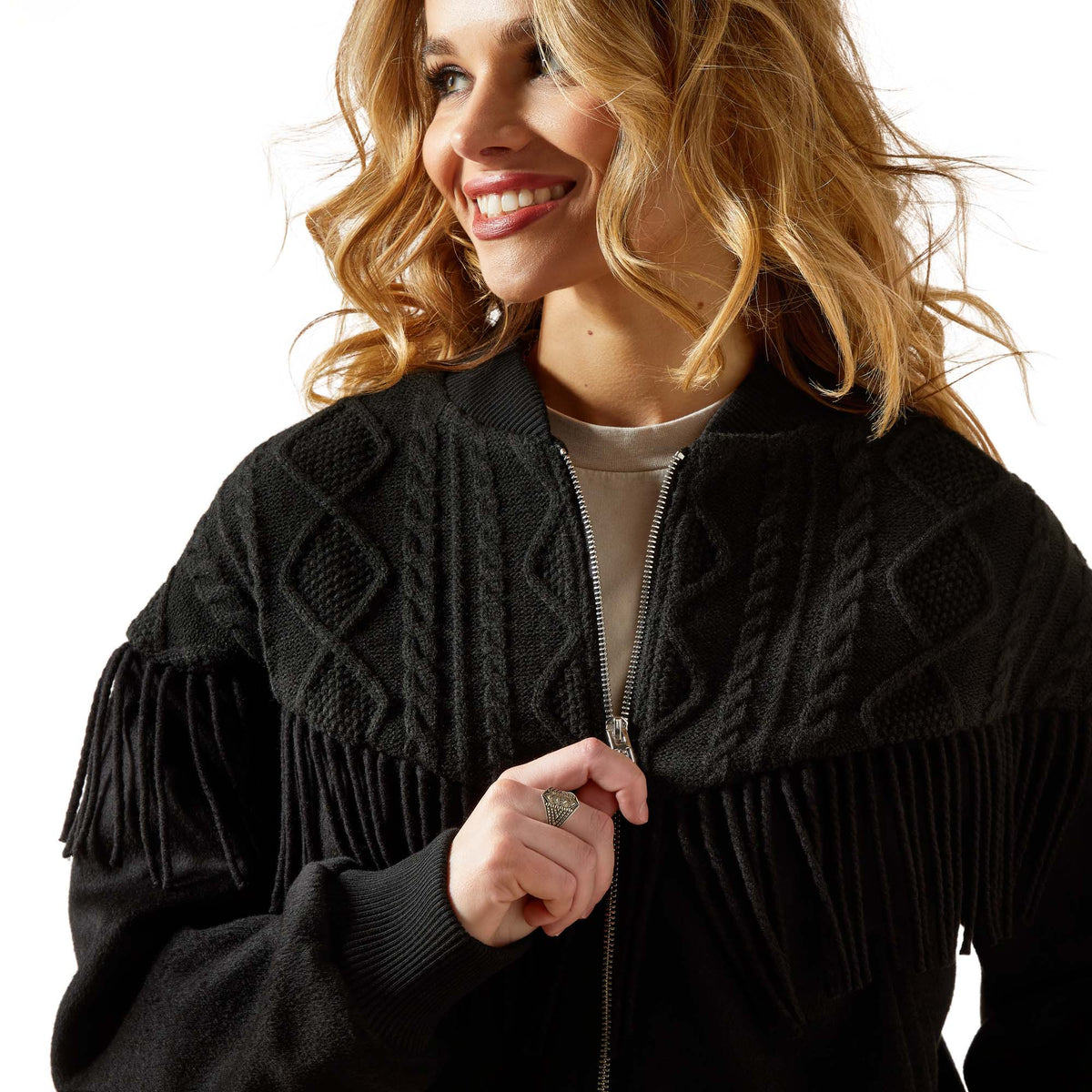 Woman wearing a black jacket with intricate patterns and fringe details on a white background