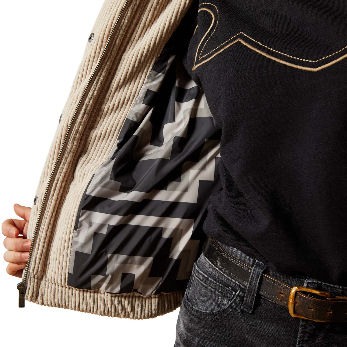 Close-up of a person wearing a jacket with a geometric pattern and black pants.
