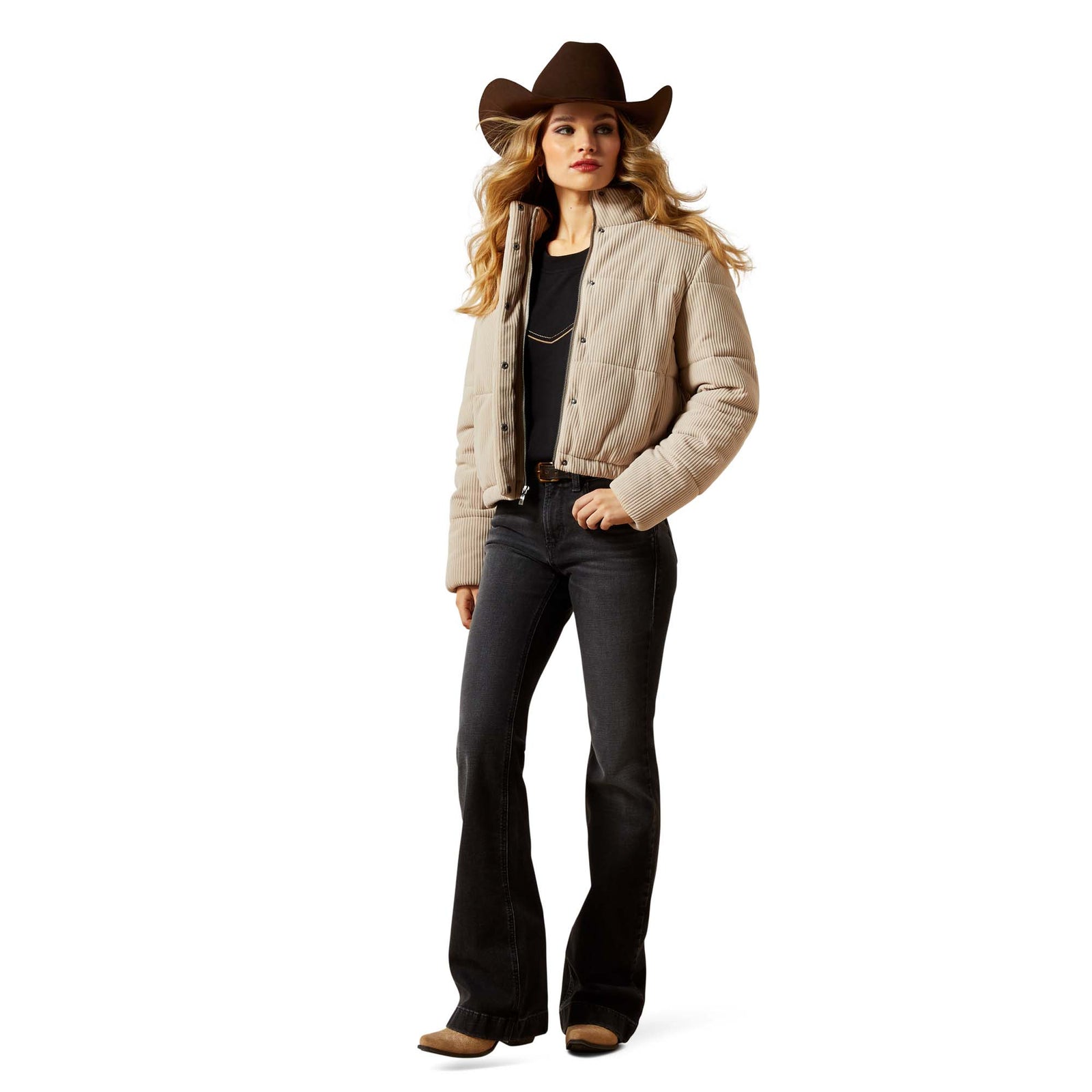 Woman wearing a beige quilted jacket, black bell-bottom pants, and a brown cowboy hat on a white background