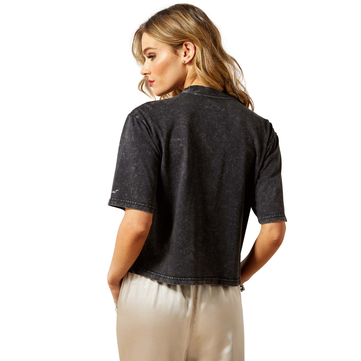 Woman wearing a black t-shirt and beige pants on a white background