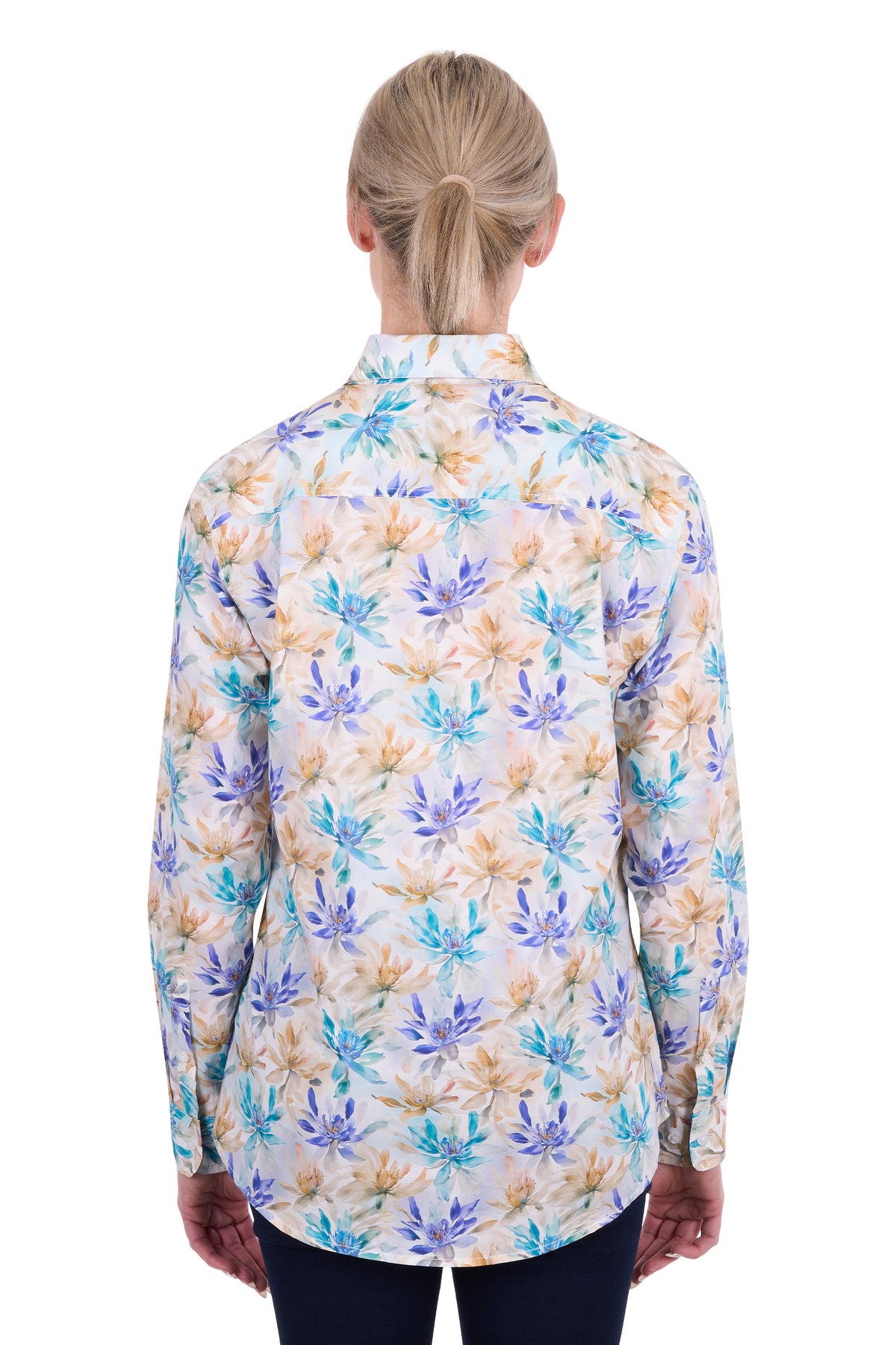 A woman viewed from the back wearing a long-sleeve button-up shirt with a multicolor floral pattern in blue, purple, and beige on a white background.
