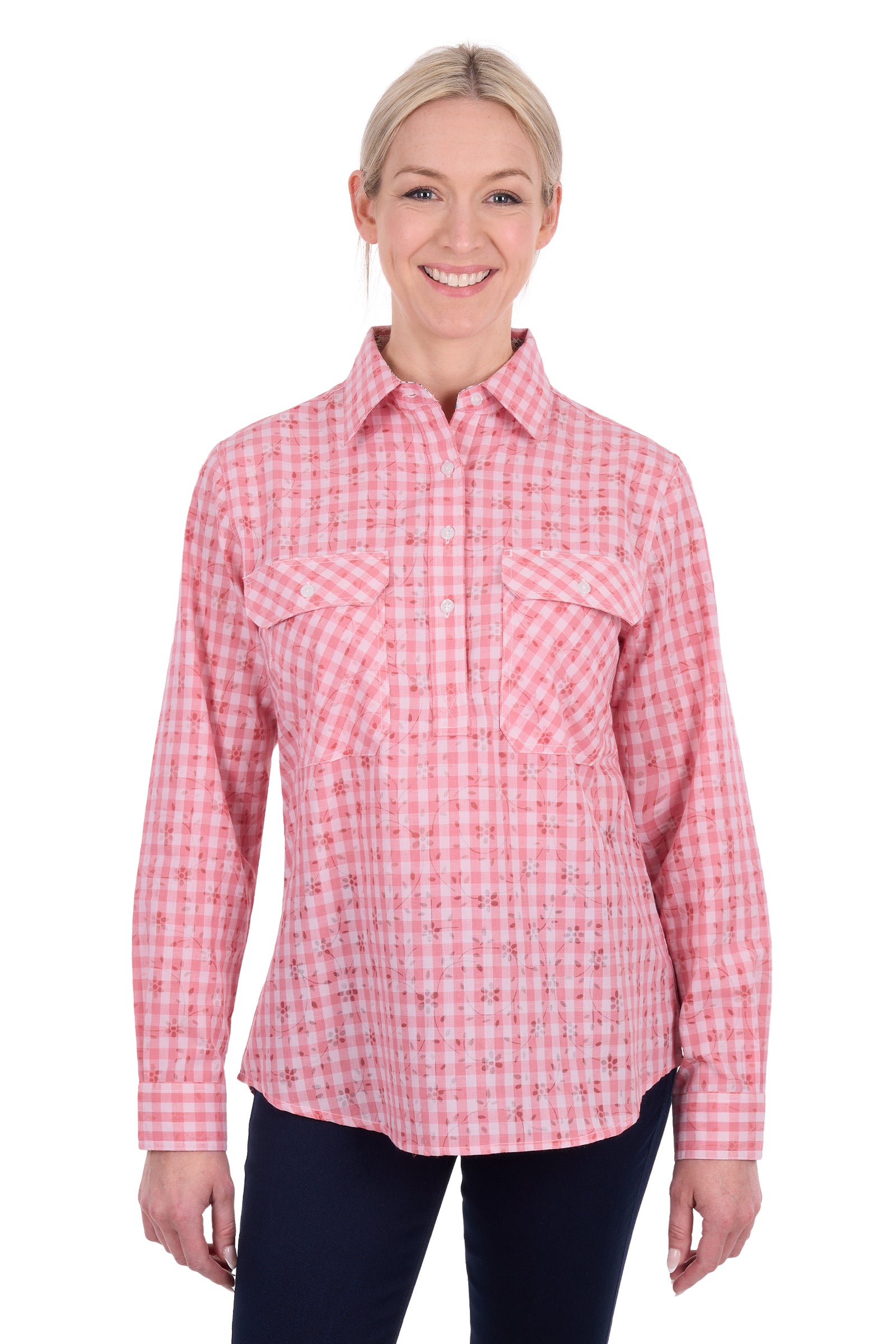 A woman modeling a pink and white gingham long-sleeve button-up shirt with two chest pockets, paired with dark pants, against a plain white background.