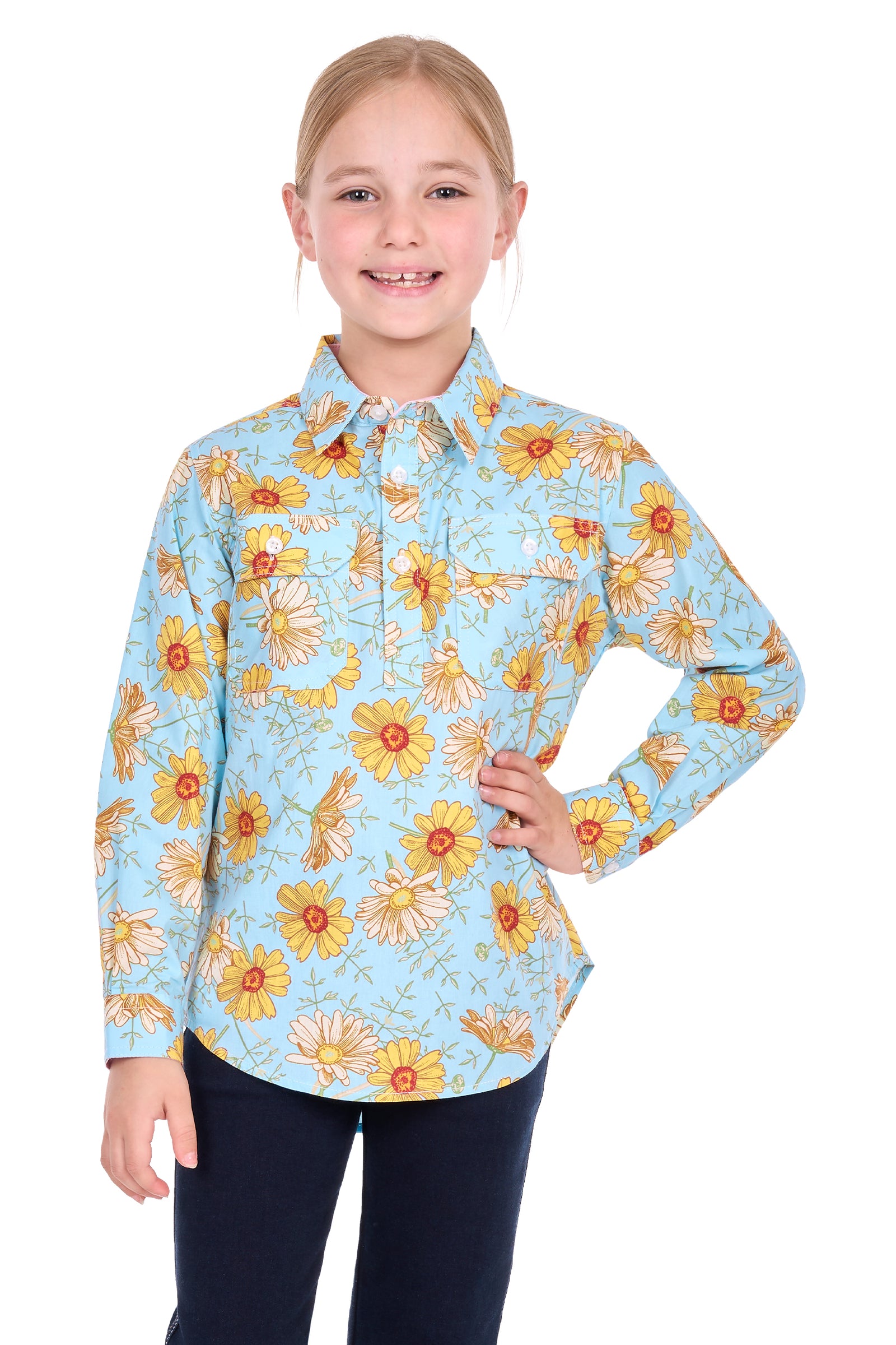 A young girl modeling a light blue long-sleeve button-up shirt with a yellow and orange floral pattern, paired with dark pants, against a solid white background.